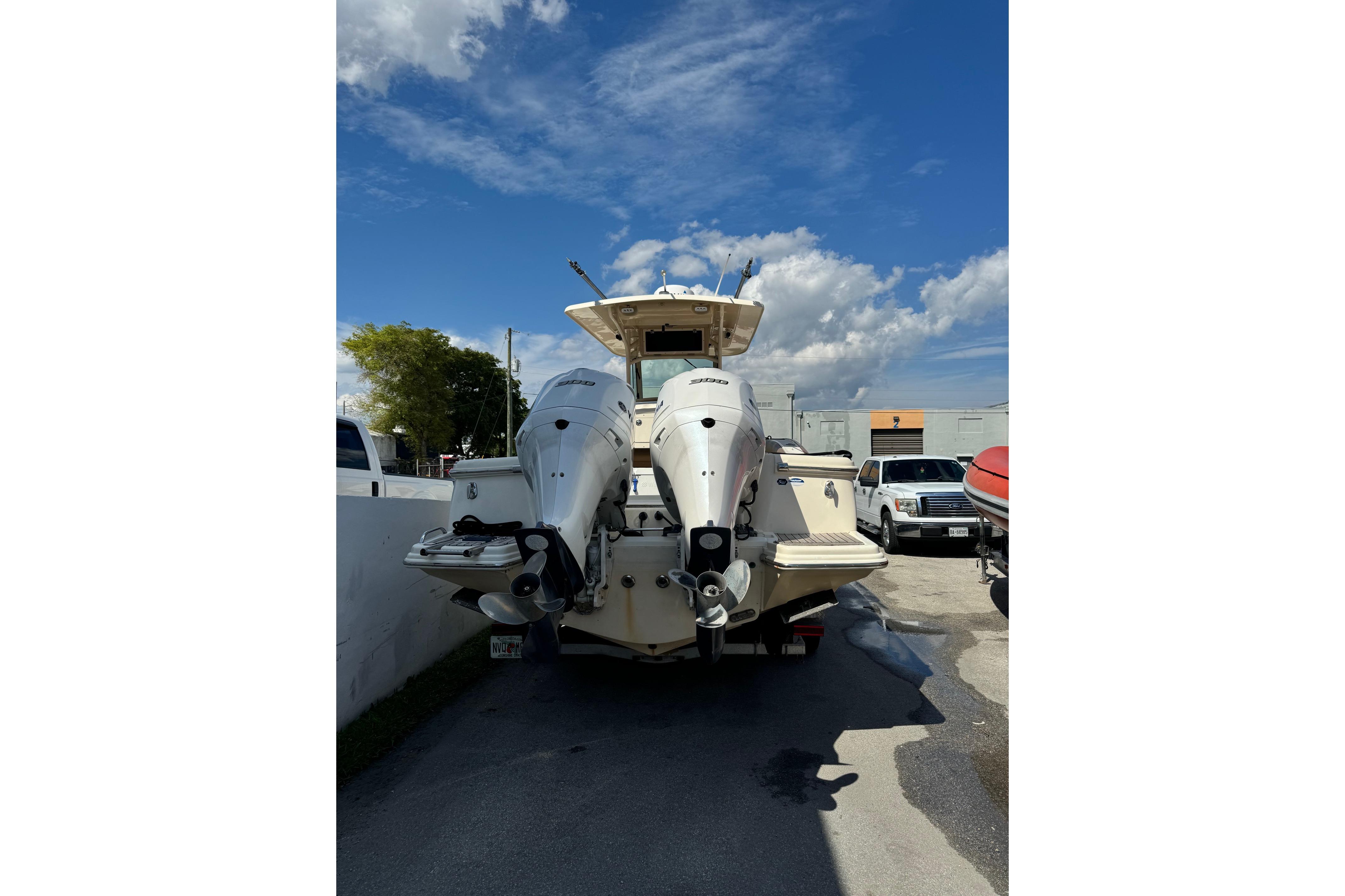 2013 Scout 275 LXF boat with dual outboard engines in a parking area.