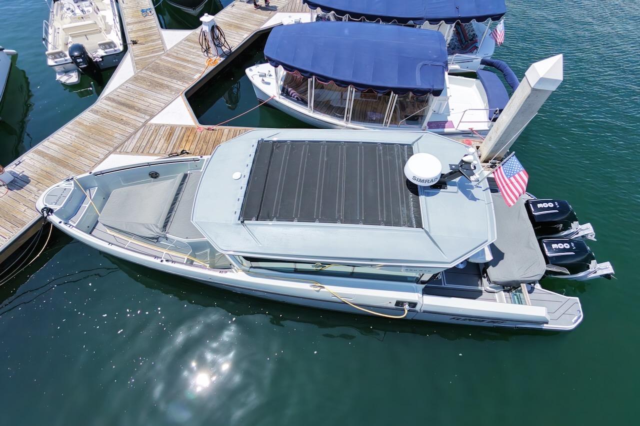 2024 Saxdor 320 GTC boat docked at marina with twin engines and American flag.