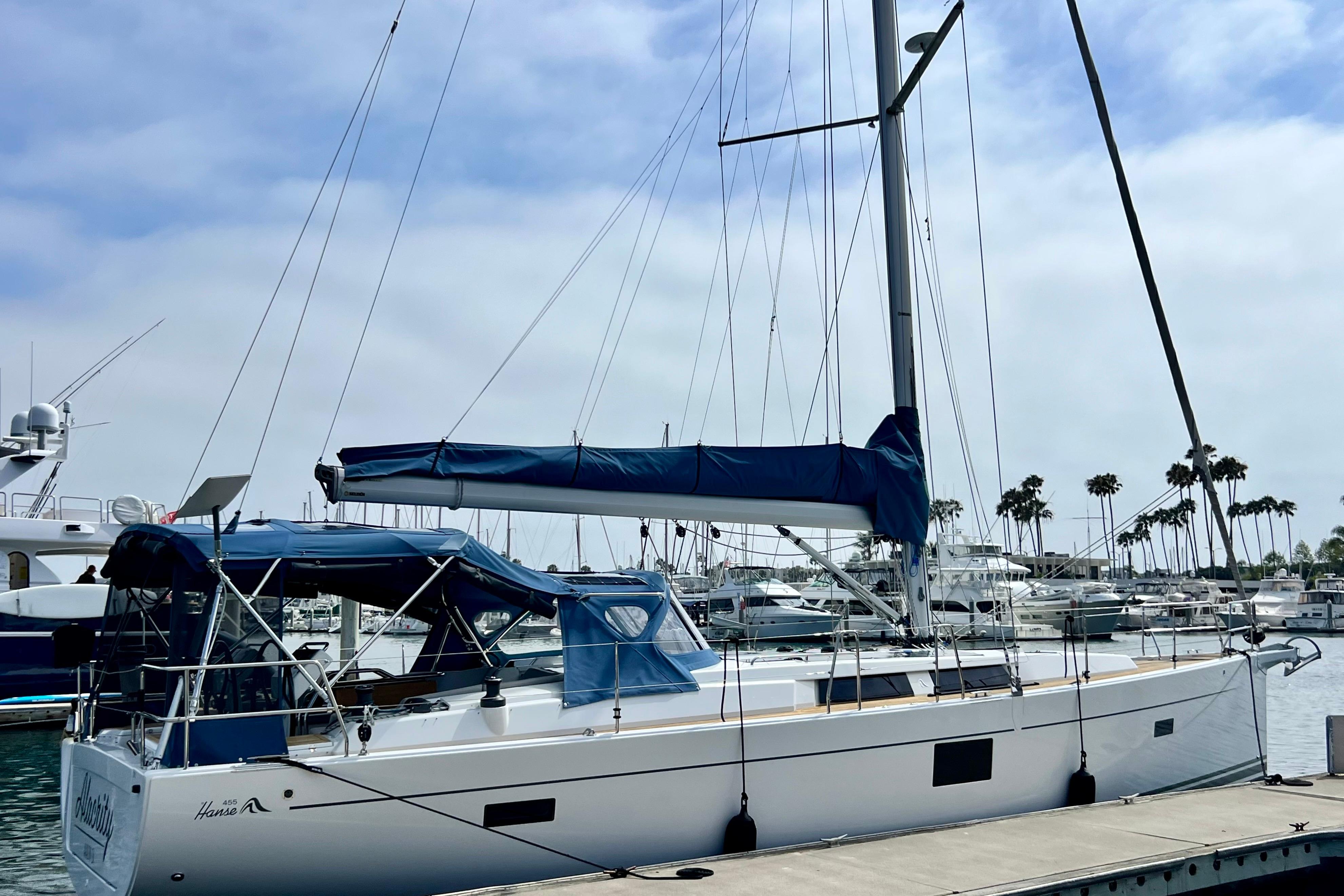 2016 Hanse 455 sailboat docked at marina with blue canopy and clear sky.