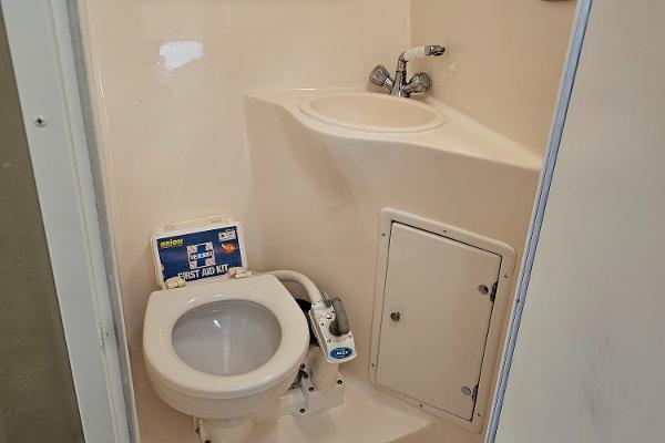 2004 Rinker Fiesta Vee 250 boat bathroom with toilet, sink, and storage compartment.