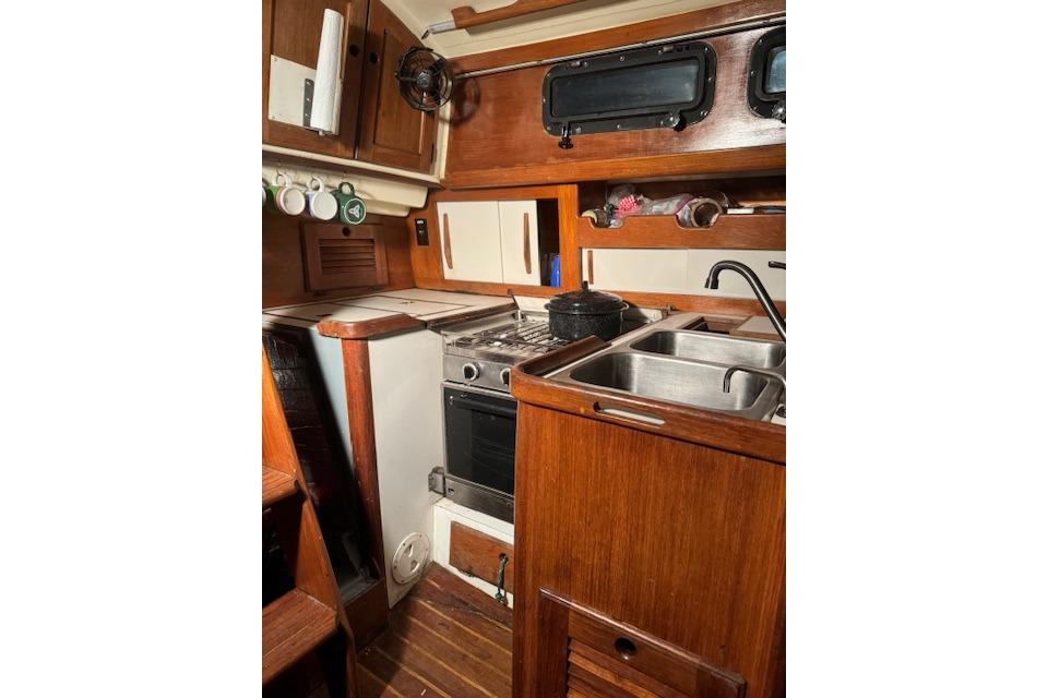 Interior of 1984 Sea Sprite 34 Yawl, featuring a compact wooden galley kitchen.