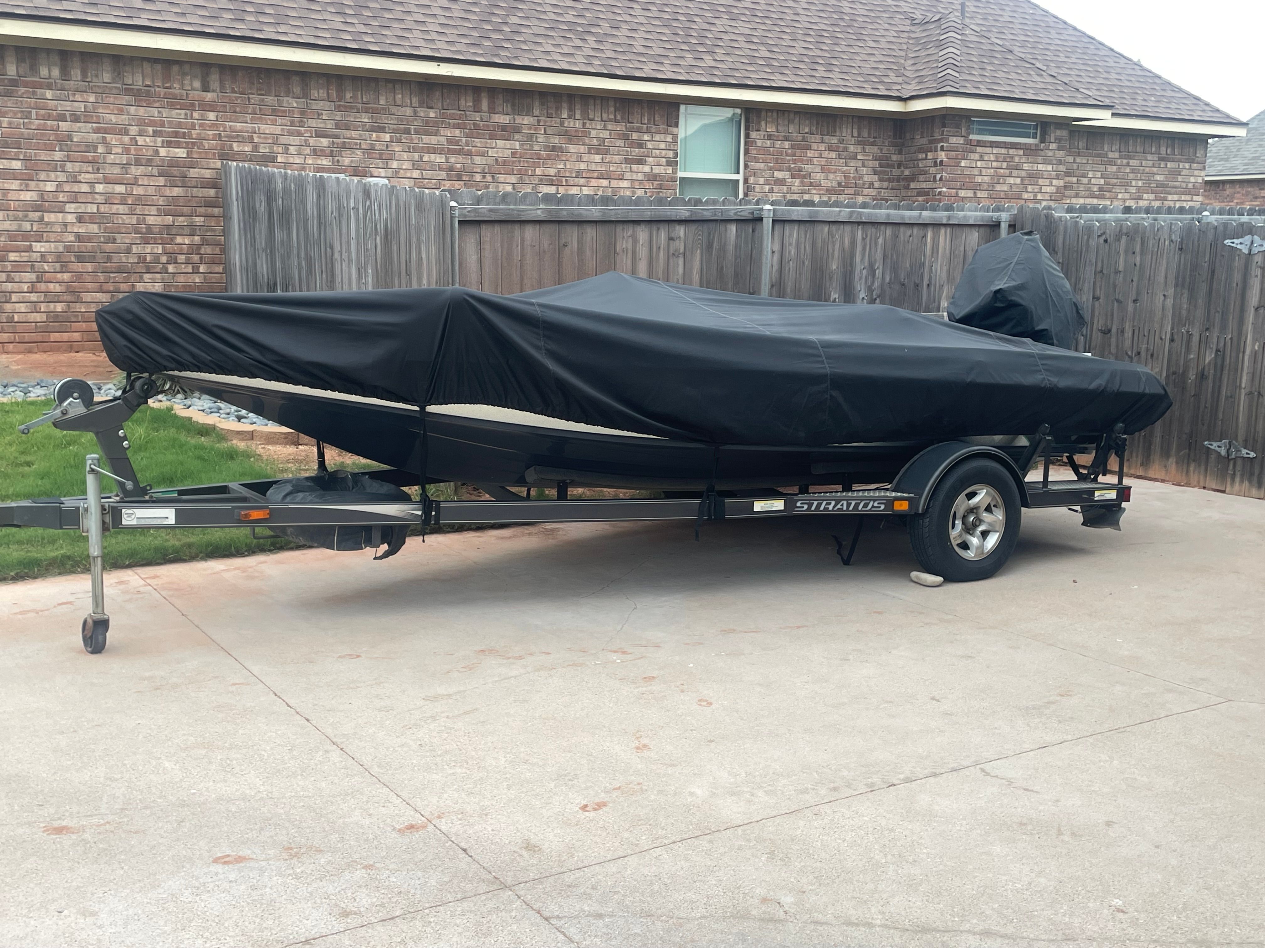A 2000 Stratos 19 SS boat, covered and parked on a trailer in a driveway.