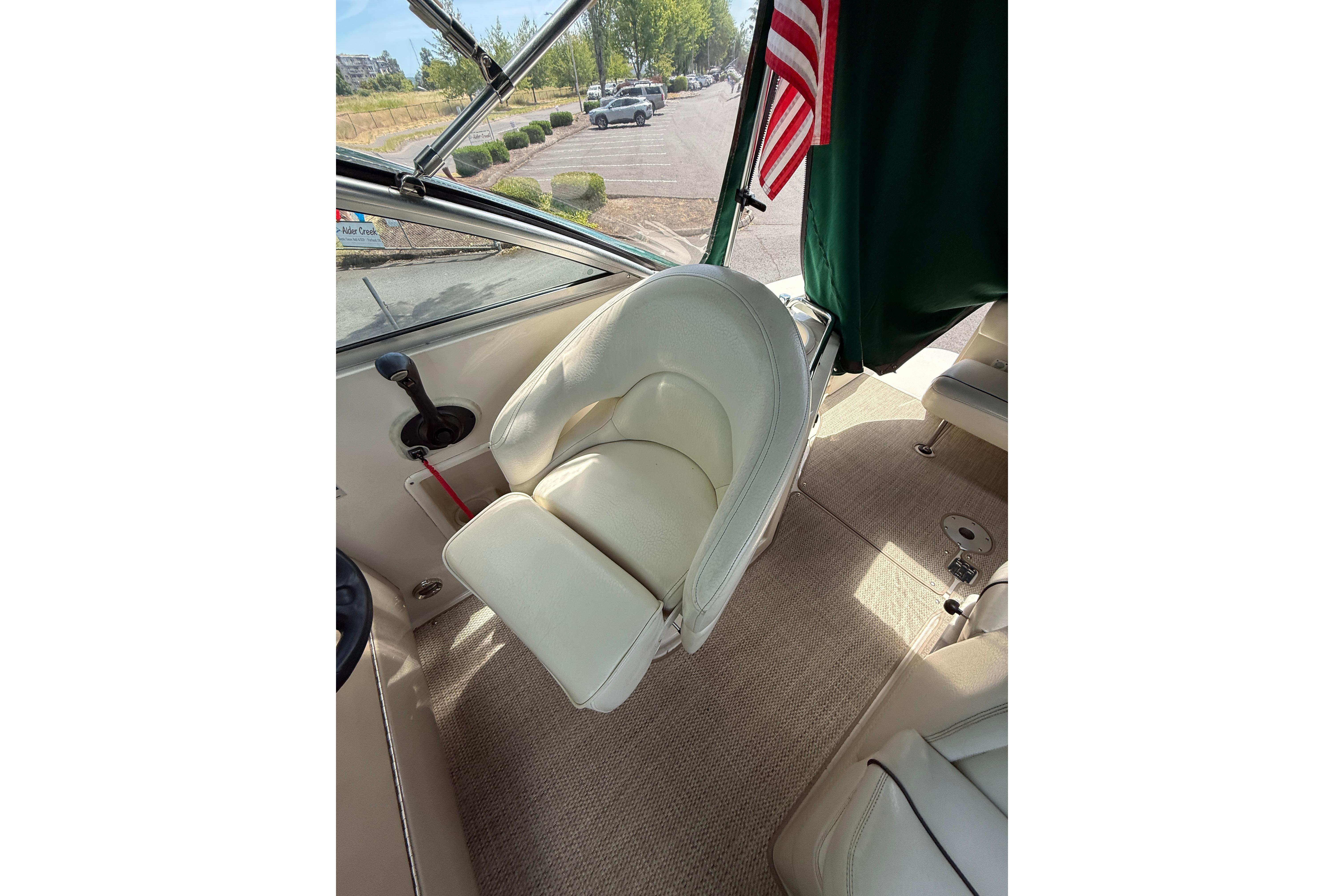 Captain's seat on 2004 Sea Ray 240 Sundancer boat, featuring beige upholstery and American flag.