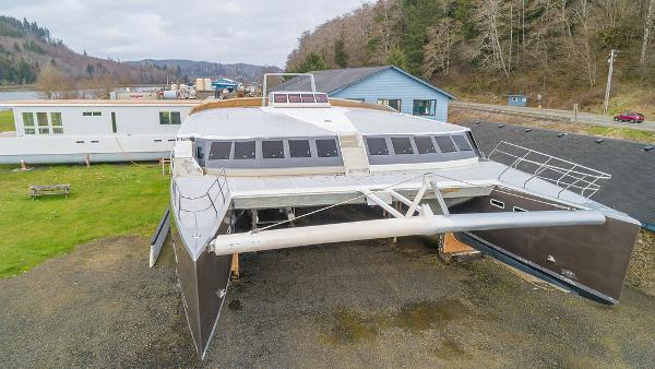 2025 Catamaran Bloomfield 86 Motorsailor docked near a building, showcasing modern design.