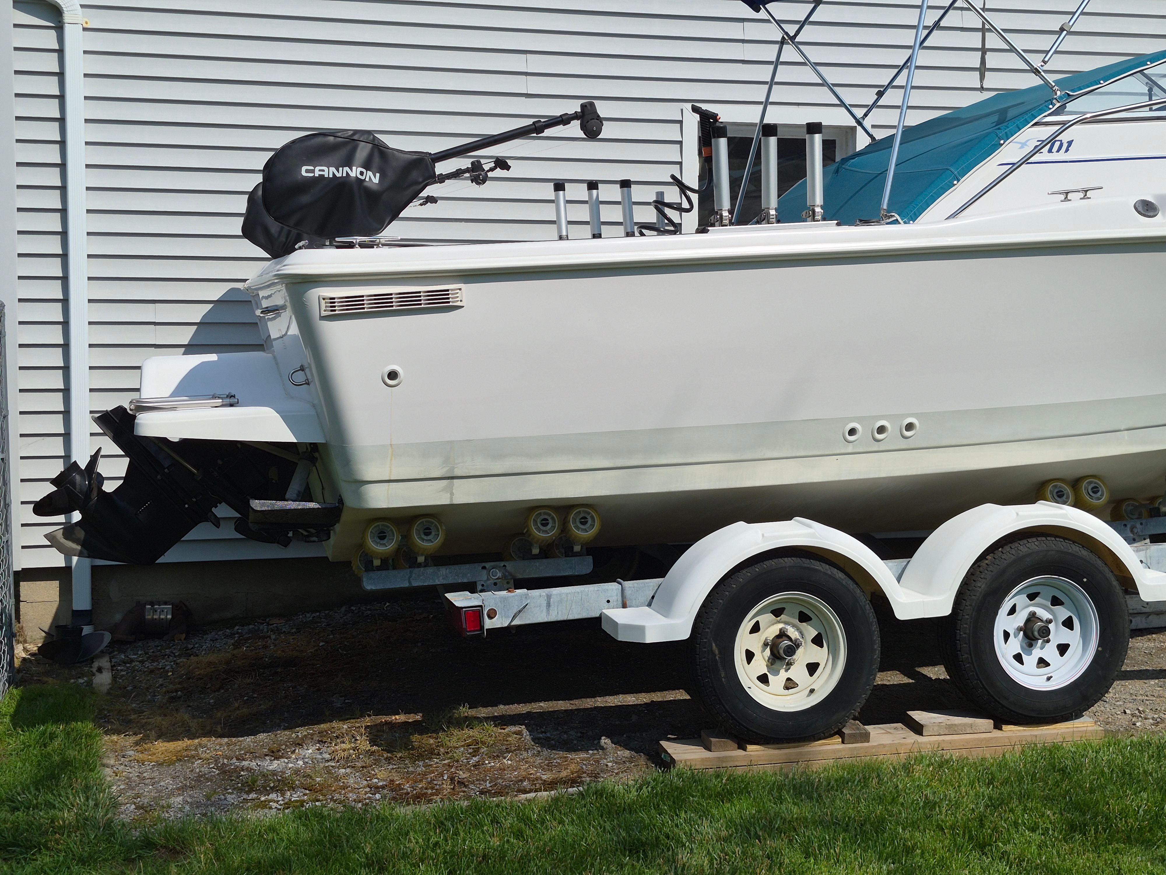 A 1999 Pro-Line 201 Walkaround boat on a trailer next to a building.