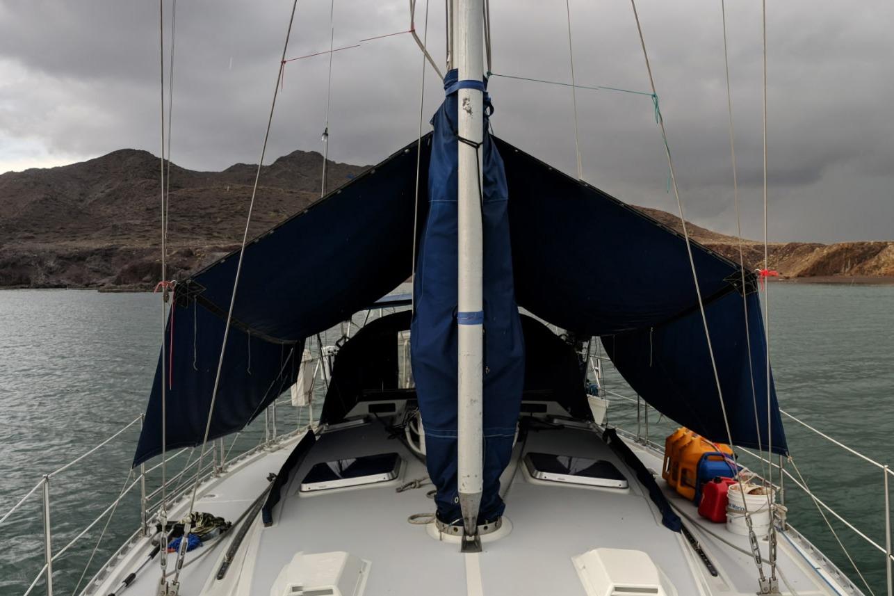1987 Norseman 400 sailboat on water, cloudy sky, rocky shoreline in background.