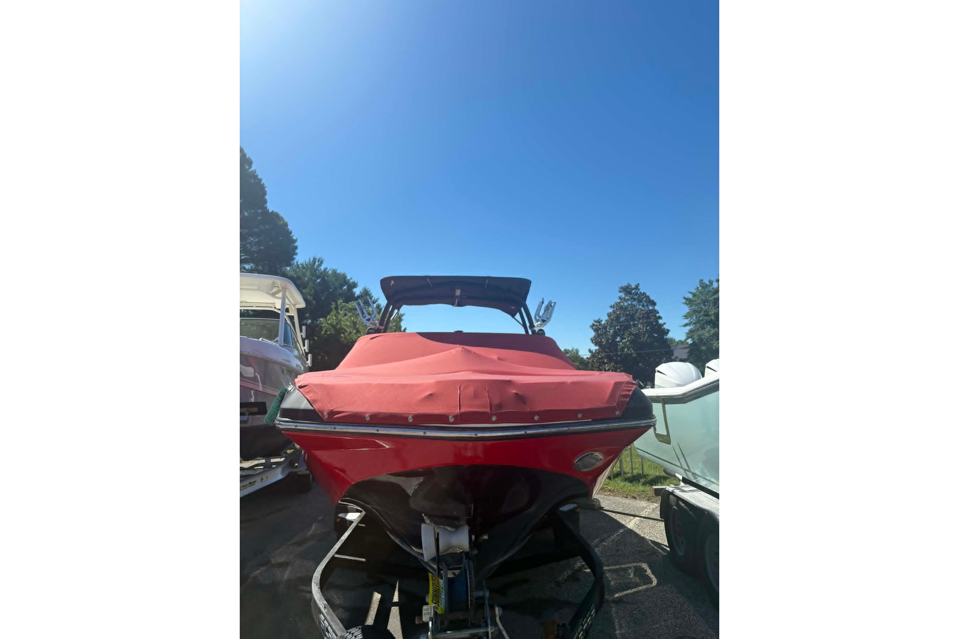 2016 Scarab 255 H.O. Impulse boat with red cover, parked outdoors under clear sky.