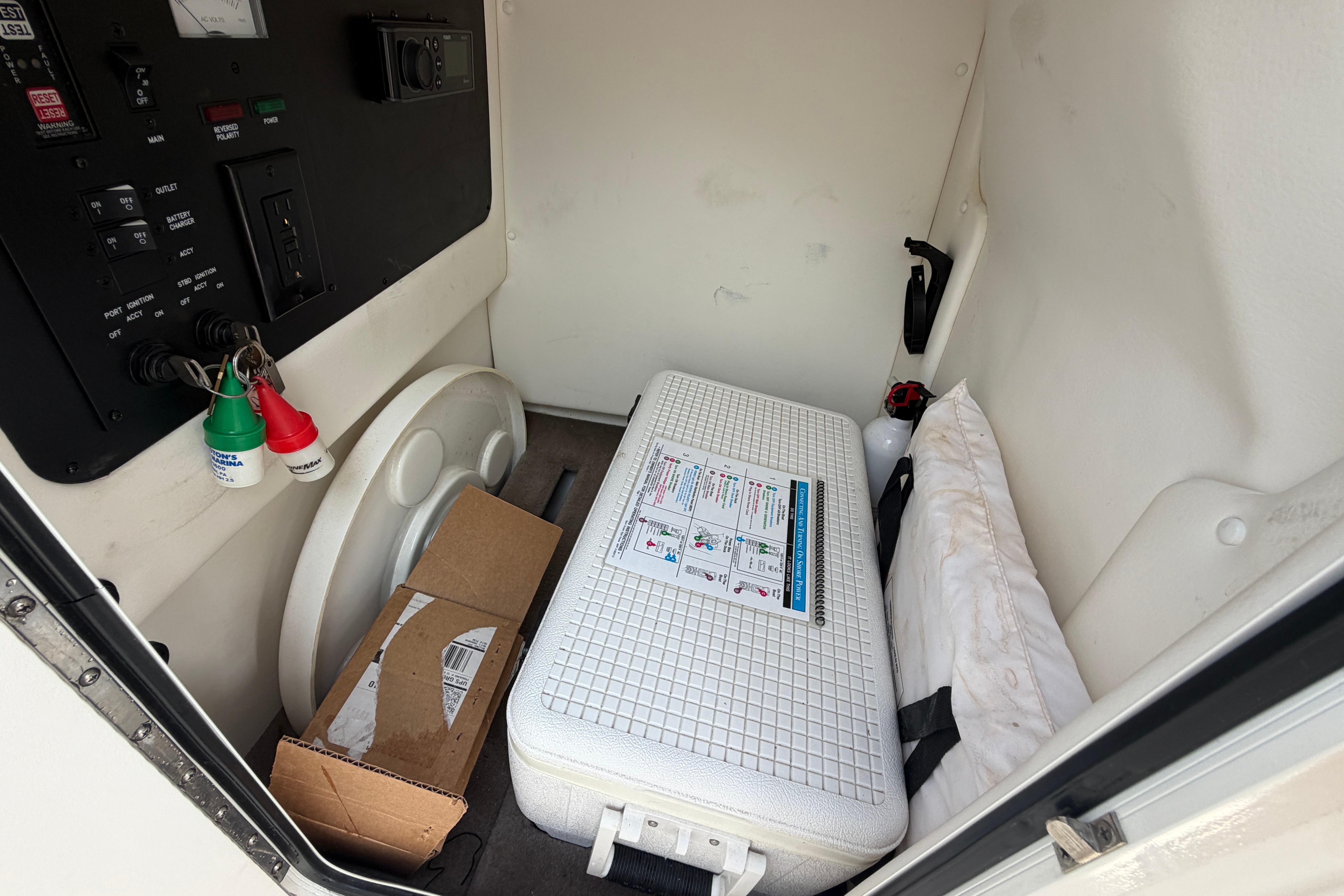 Storage compartment of a 2013 Sea Ray 300 SLX boat with safety equipment and manuals.