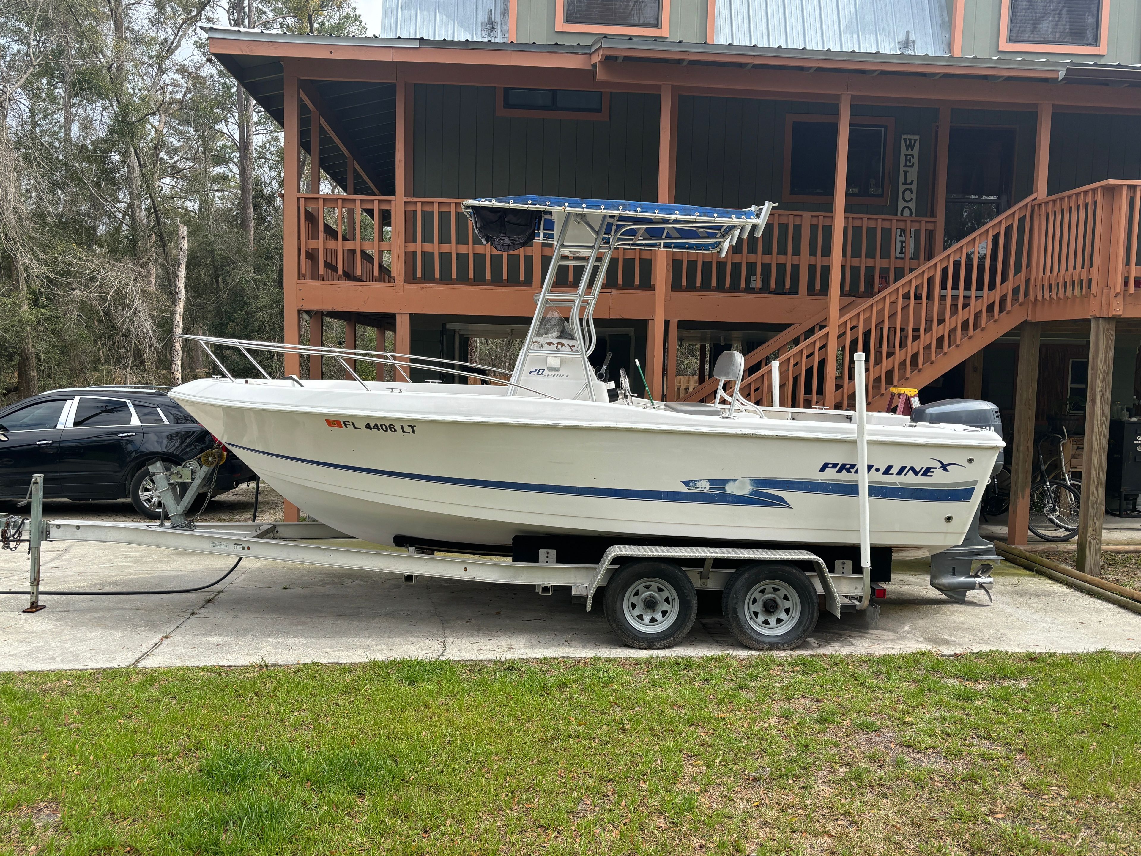 2003 Pro-Line Sport 20 boat on trailer in front of house.