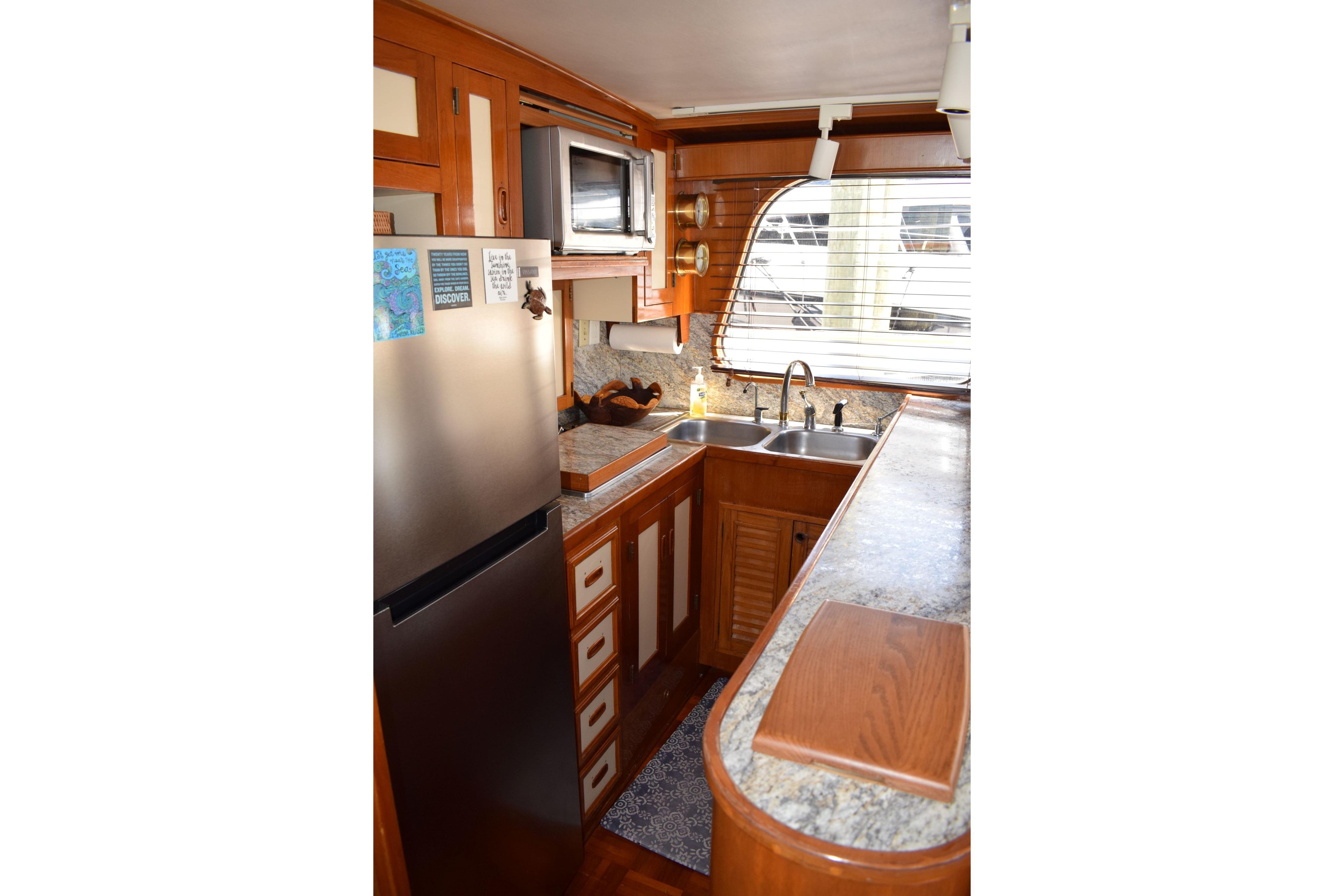 1980 Cheoy Lee 52 Motorsailer kitchen with wood cabinetry, stainless steel appliances, and dual sinks.