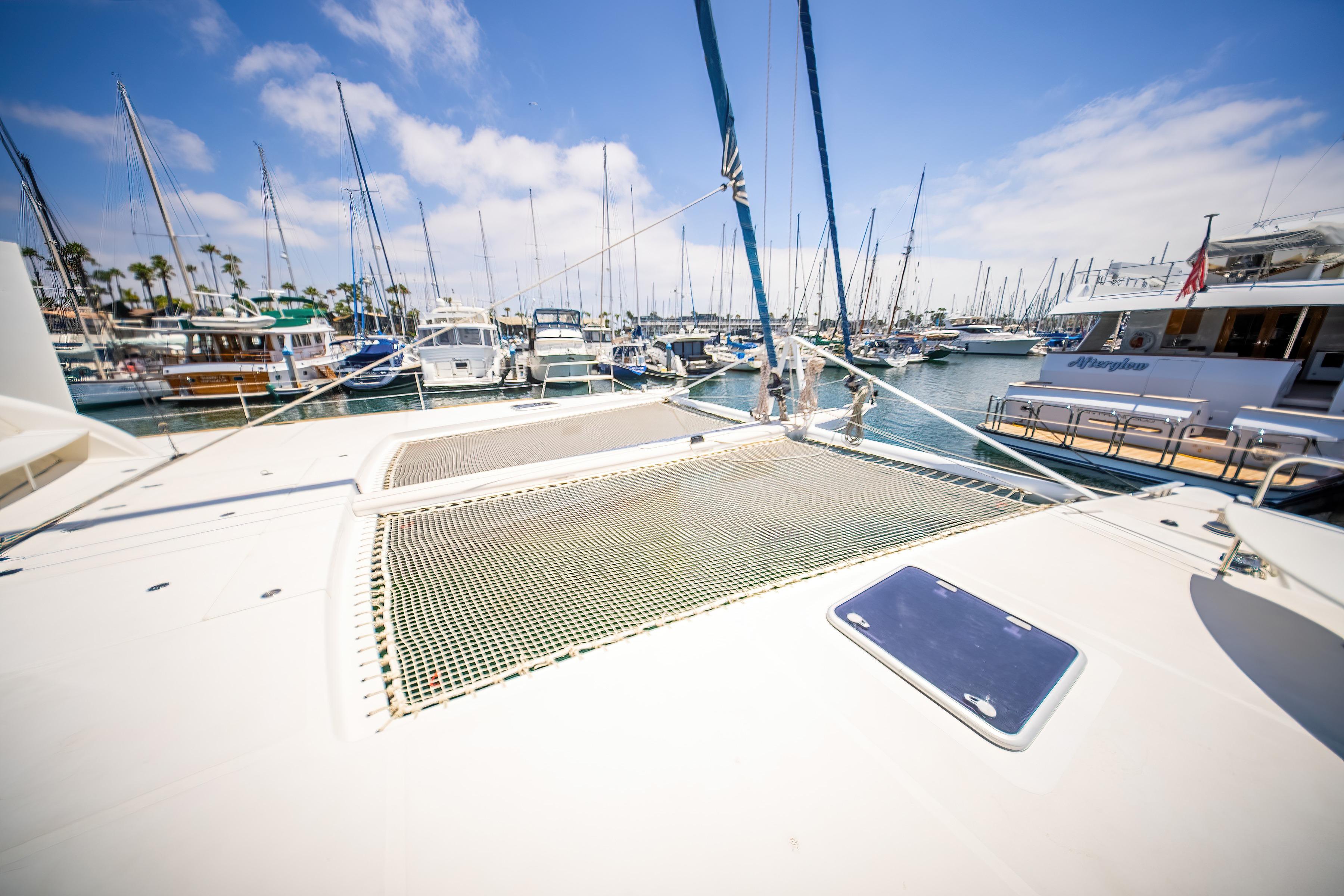 2009 Catana 65 yacht docked in a sunny marina with sailboats.