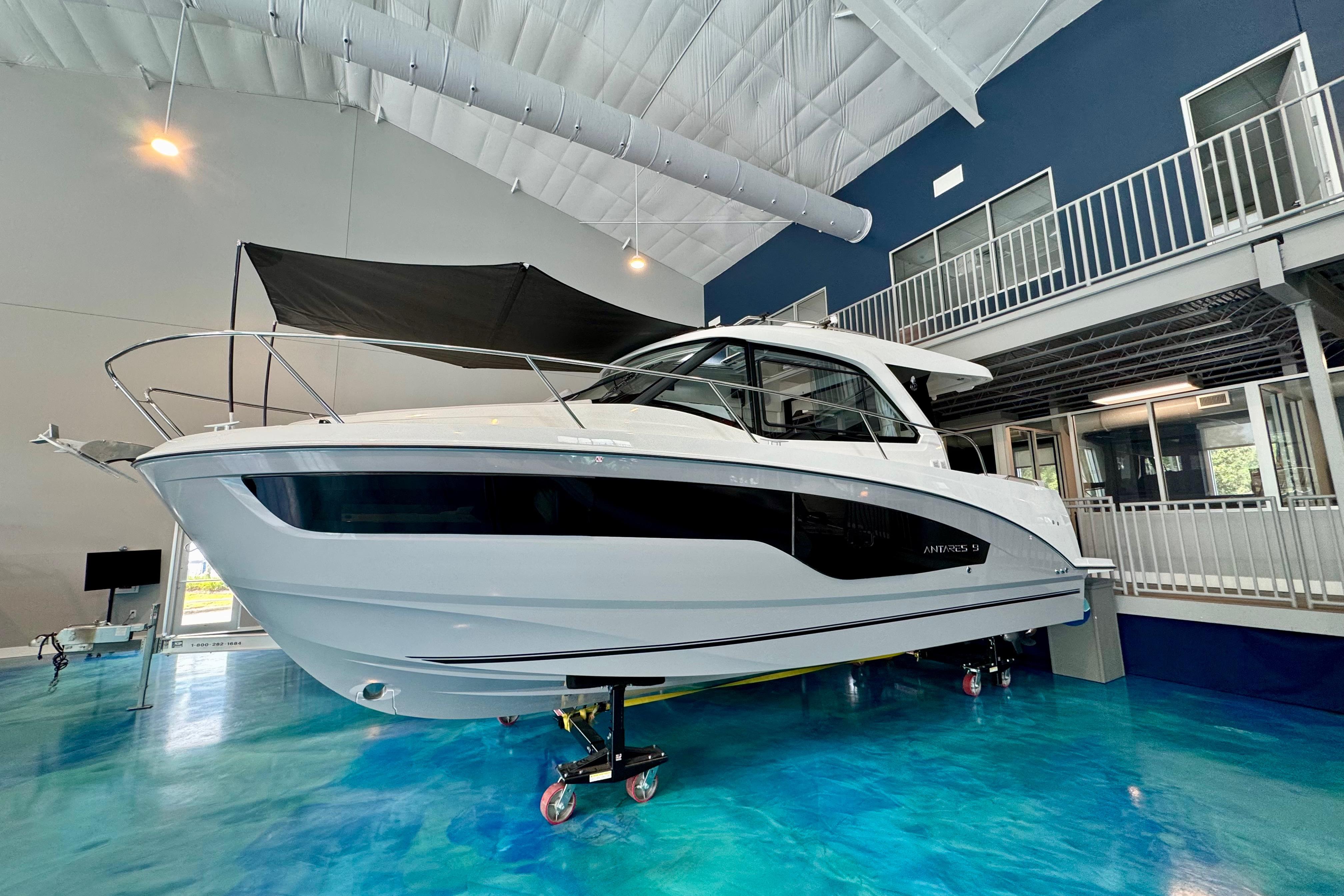 2026 Beneteau Antares 9 boat displayed indoors on a blue floor.