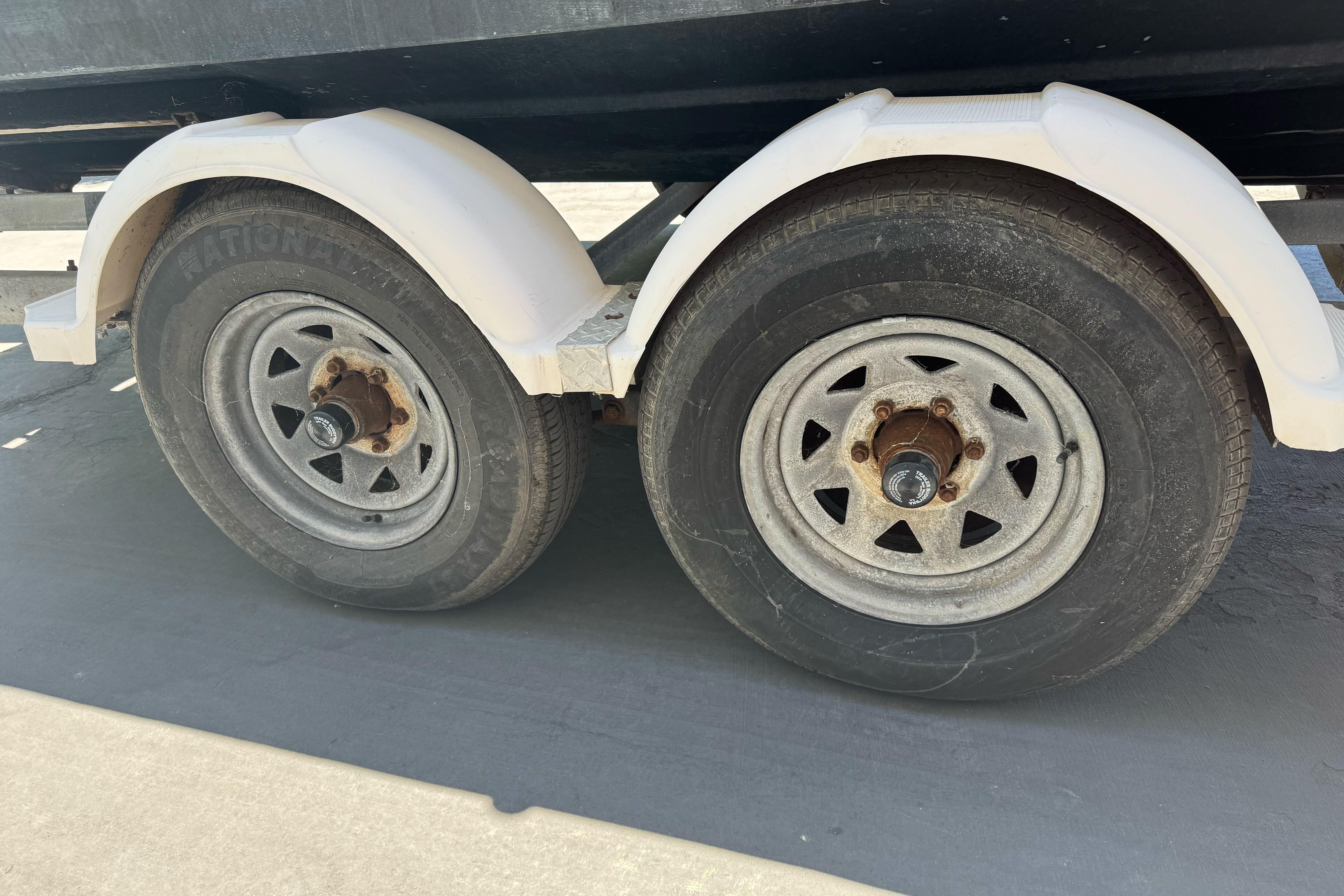 Trailer wheels of a 2004 Trophy 2359 WA boat, featuring dual axles and white fenders.