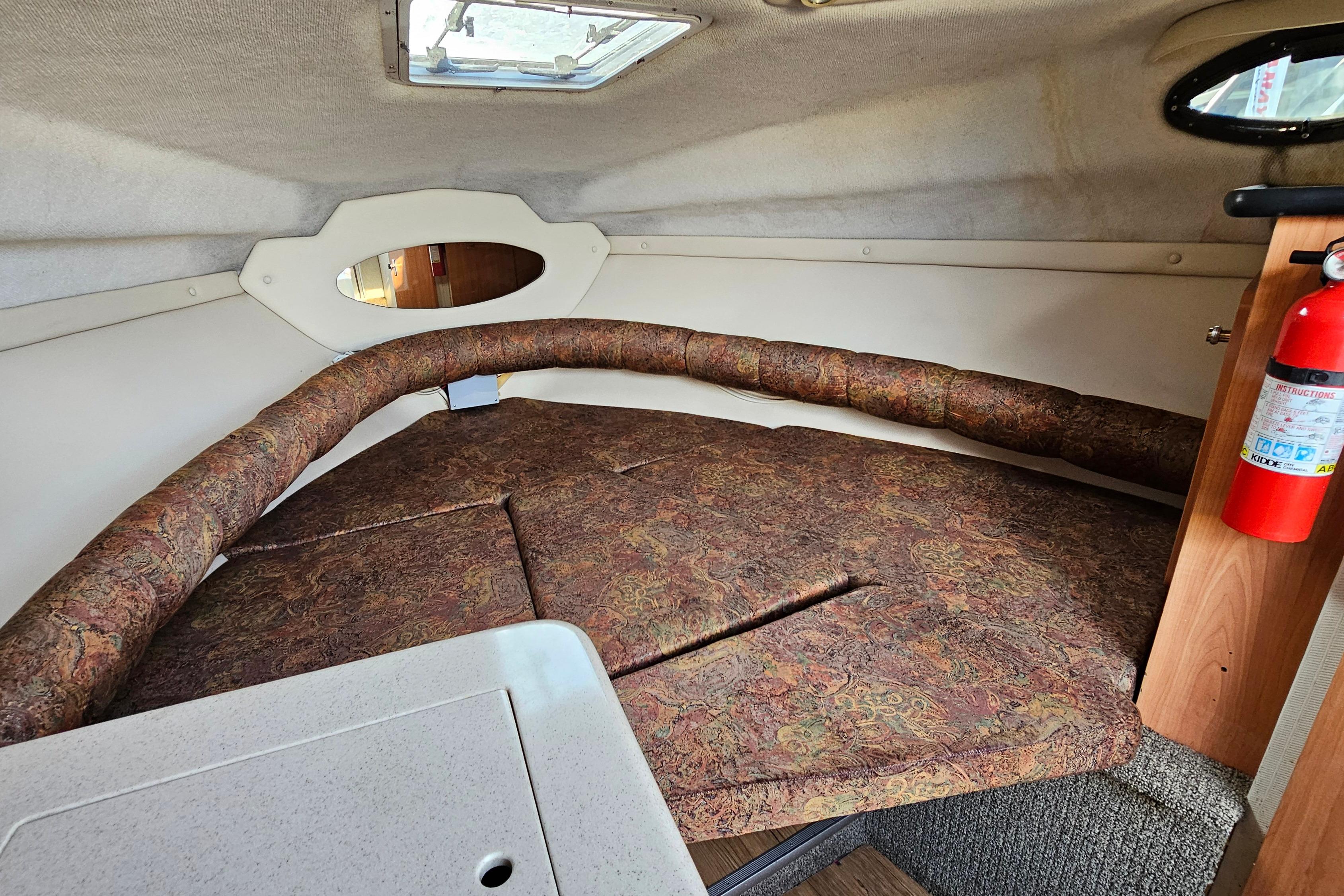 1999 Regal Commodore 258 cabin interior with patterned cushions and a fire extinguisher.