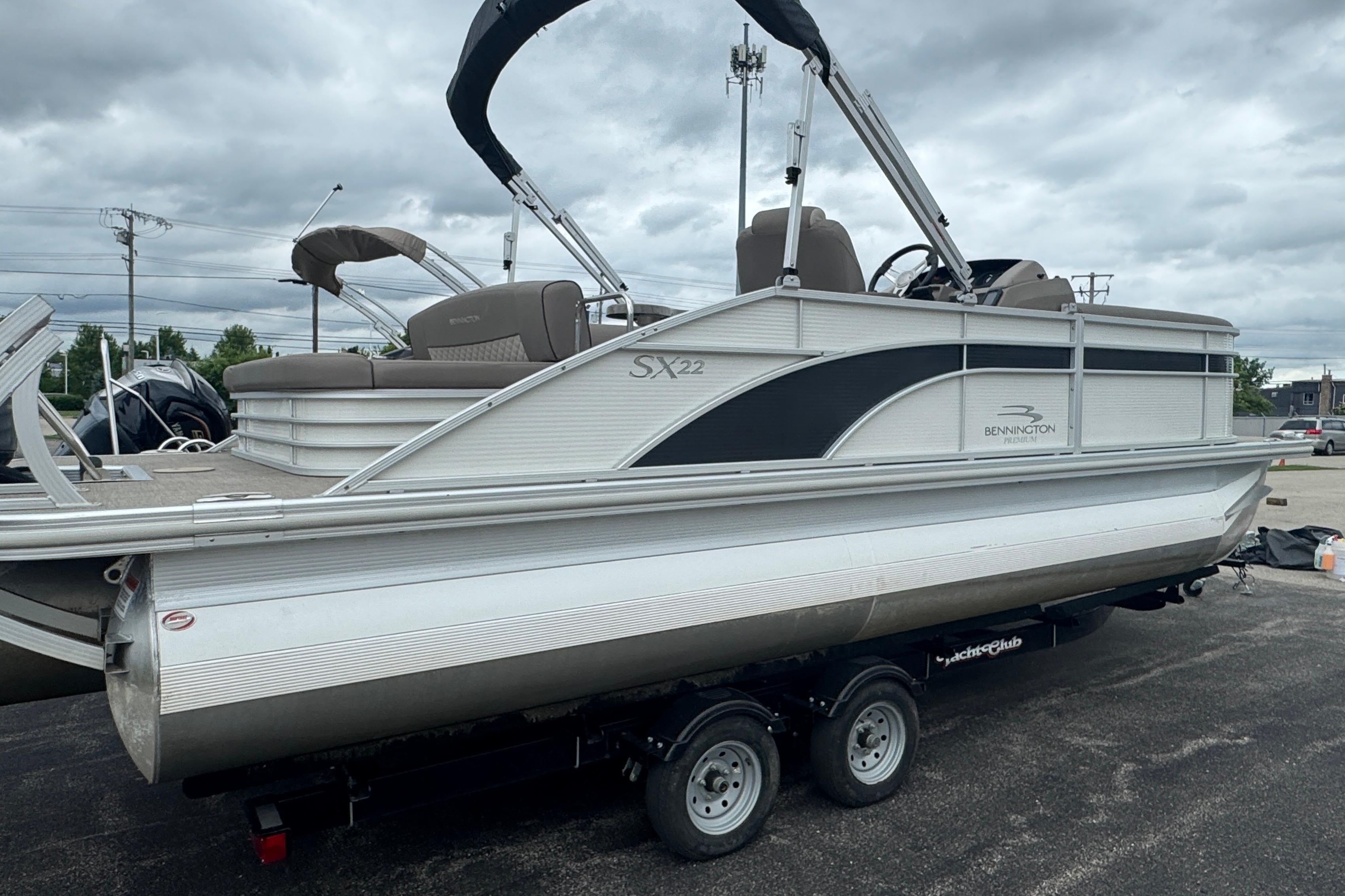 2019 Bennington SX 22 SSBXP pontoon boat on trailer, parked outdoors under cloudy sky.