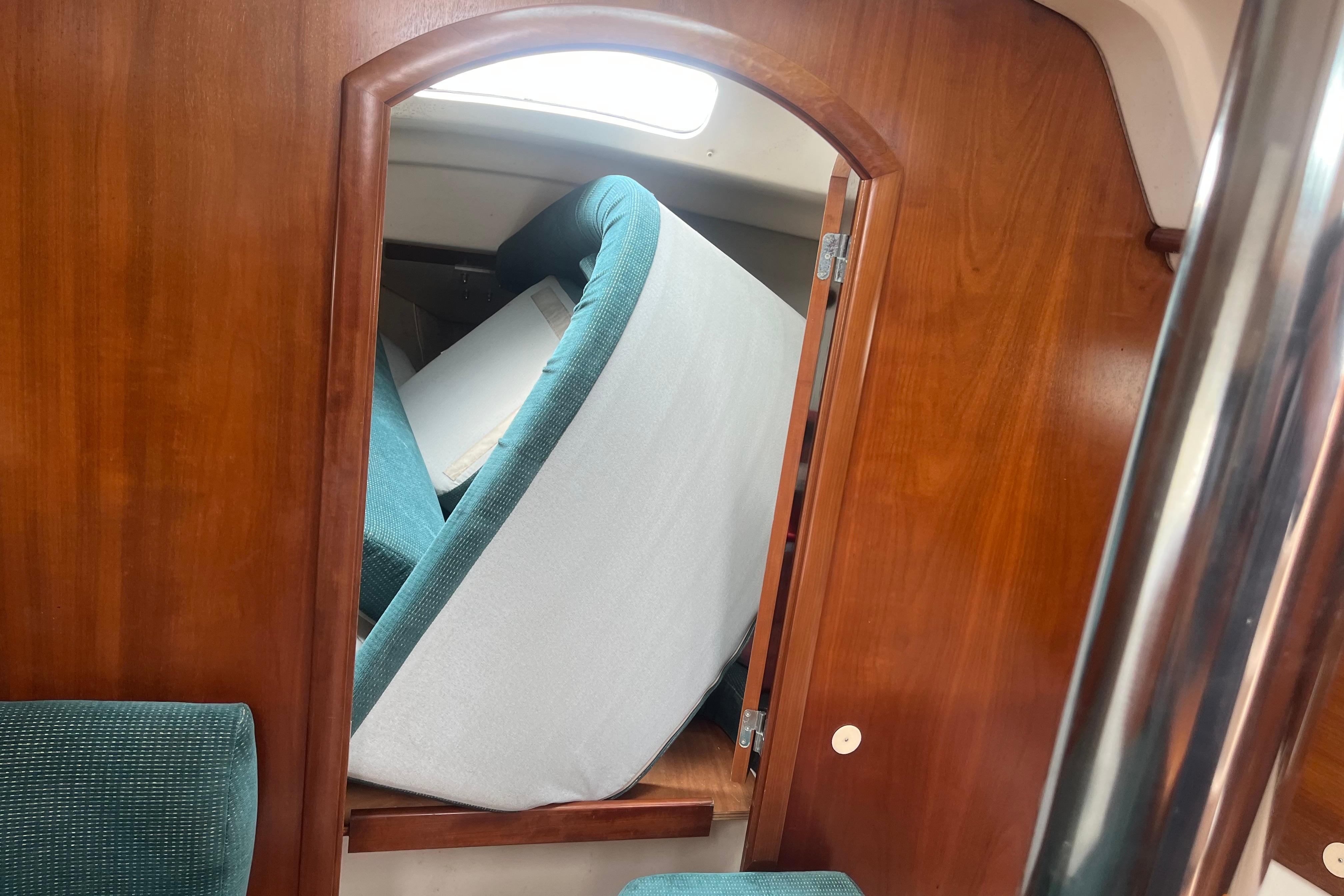 Interior of 1999 Benneteau 321 Oceanis with teal cushions and wooden paneling.
