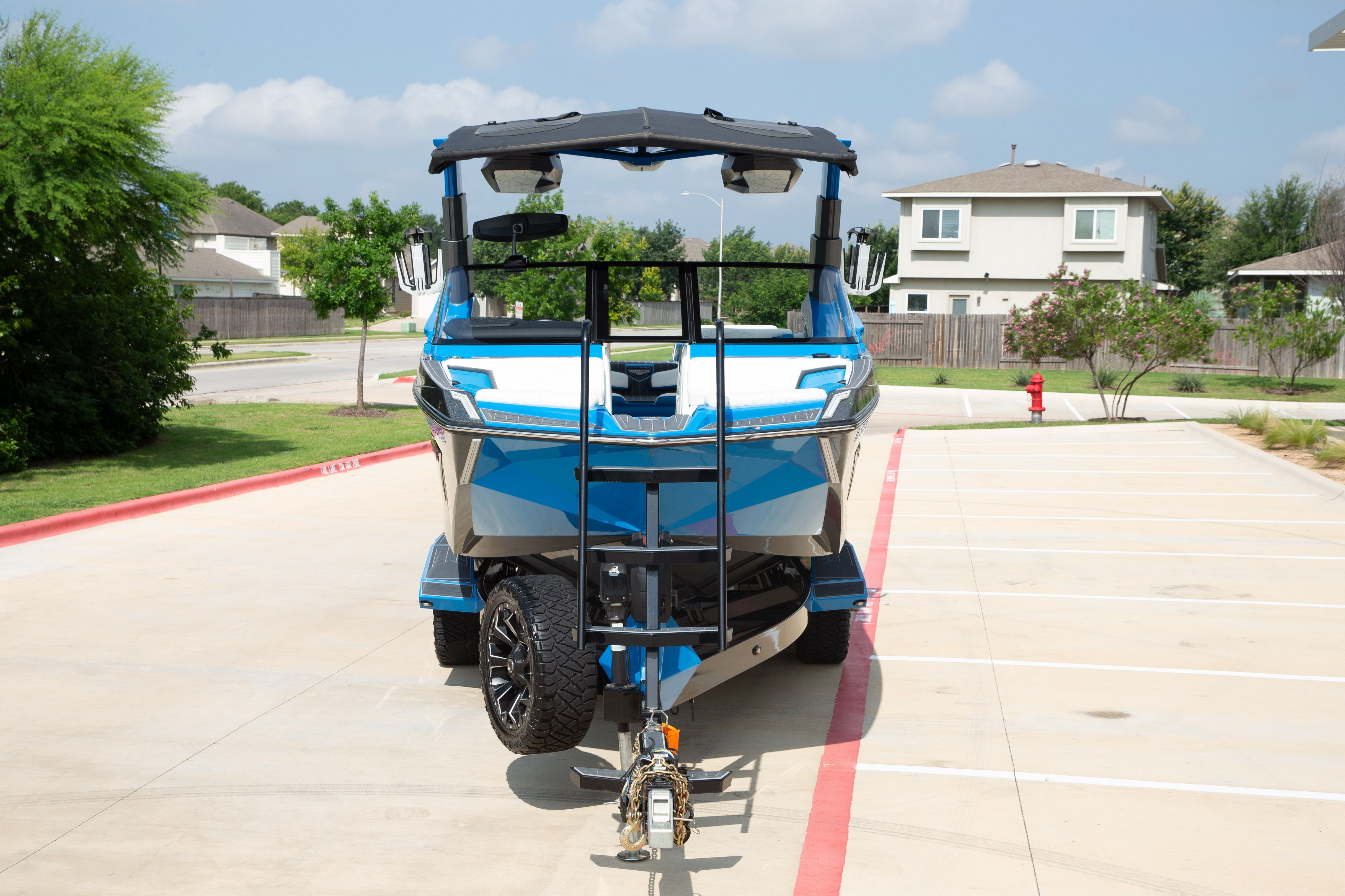 A blue boat on a trailer in a parking lot.