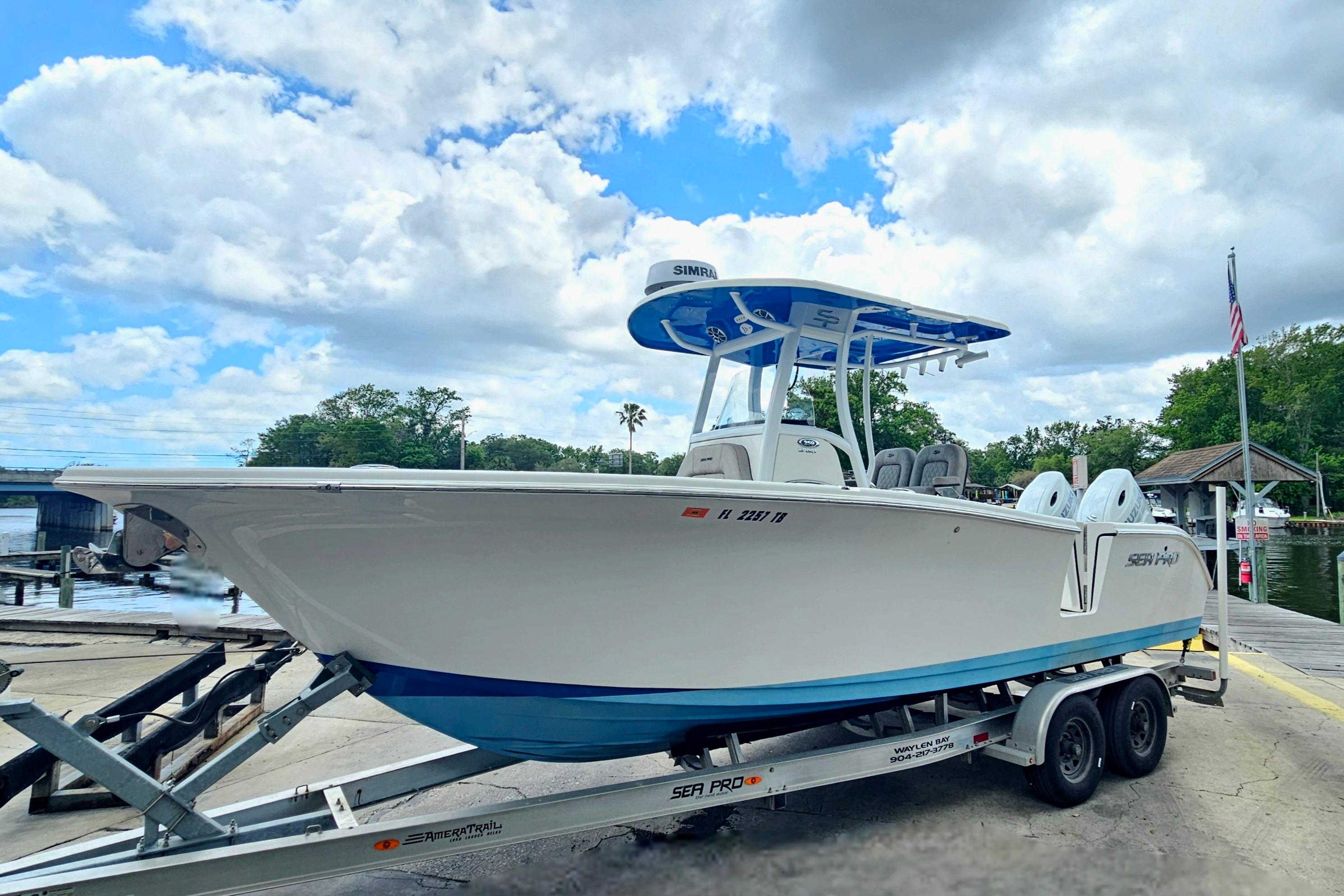2021 Sea Pro 259 Center Console boat on trailer by waterfront under cloudy sky.