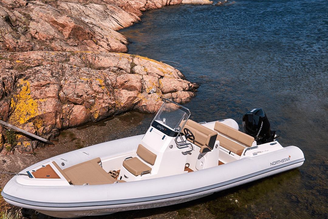 2026 Northstar Orion 7 boat docked by rocky shoreline in clear water.