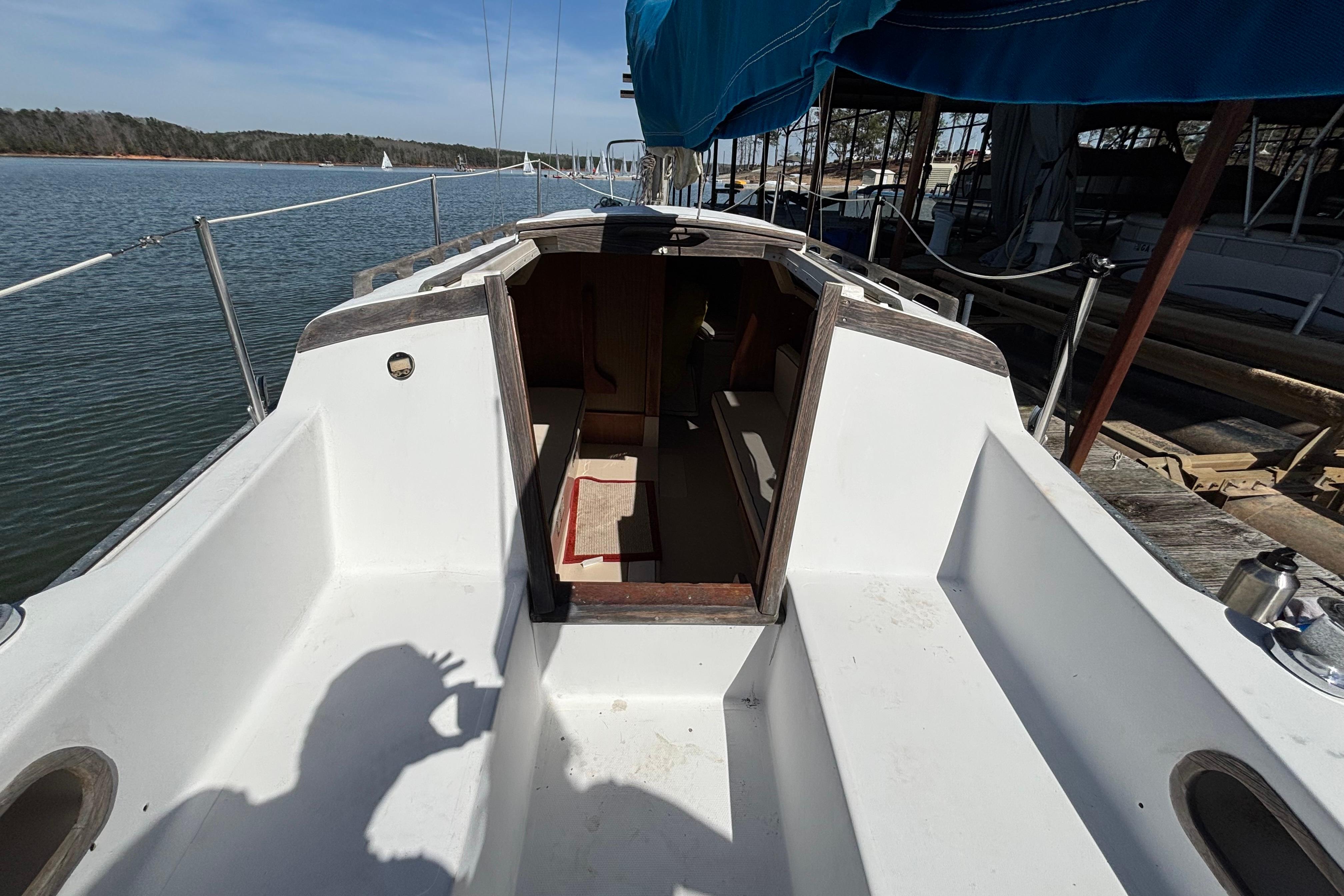 1983 Catalina 25 sailboat cockpit with open cabin, docked by calm waters.
