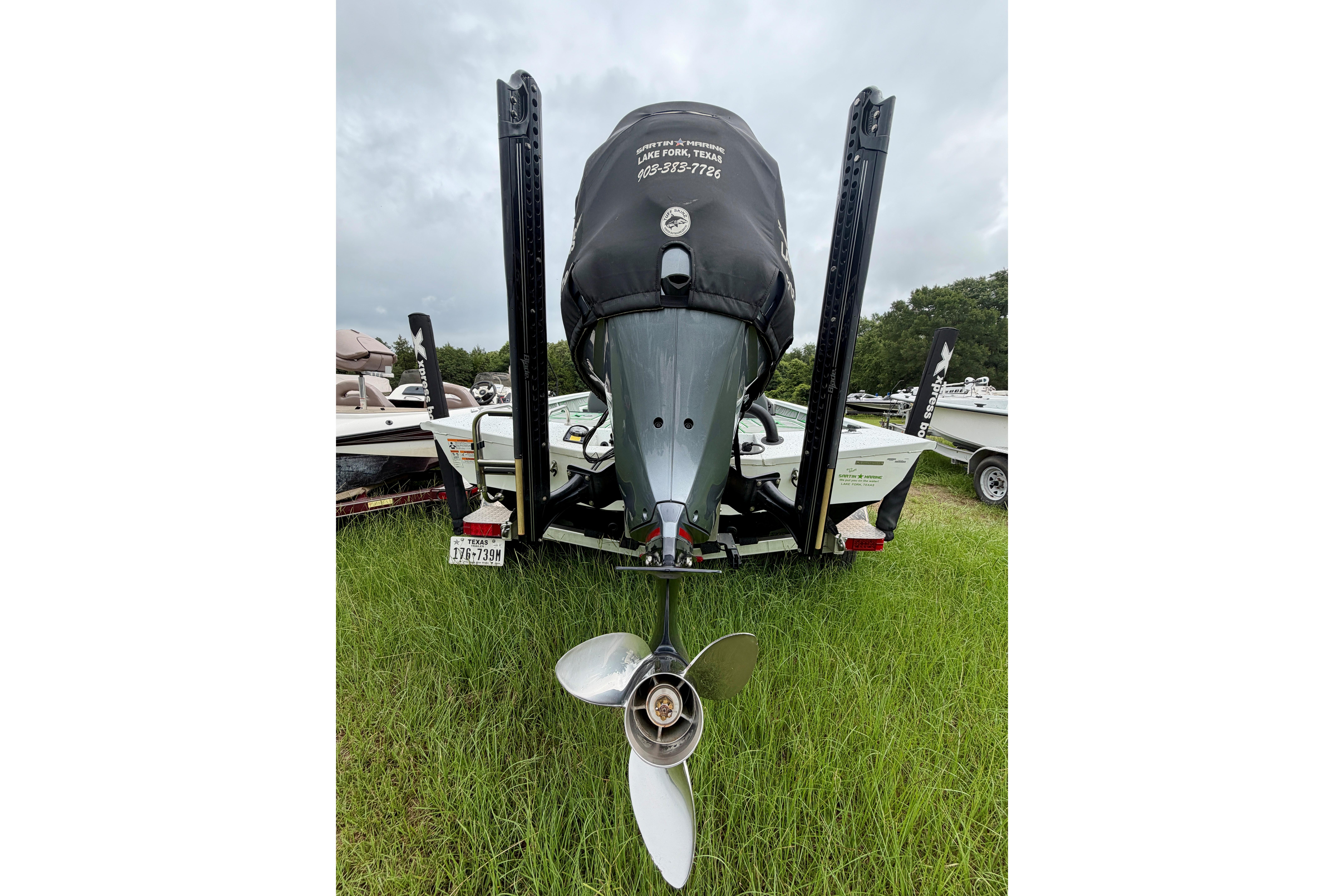 Rear view of 2022 Xpress X21 Pro boat with motor and propeller on grass.
