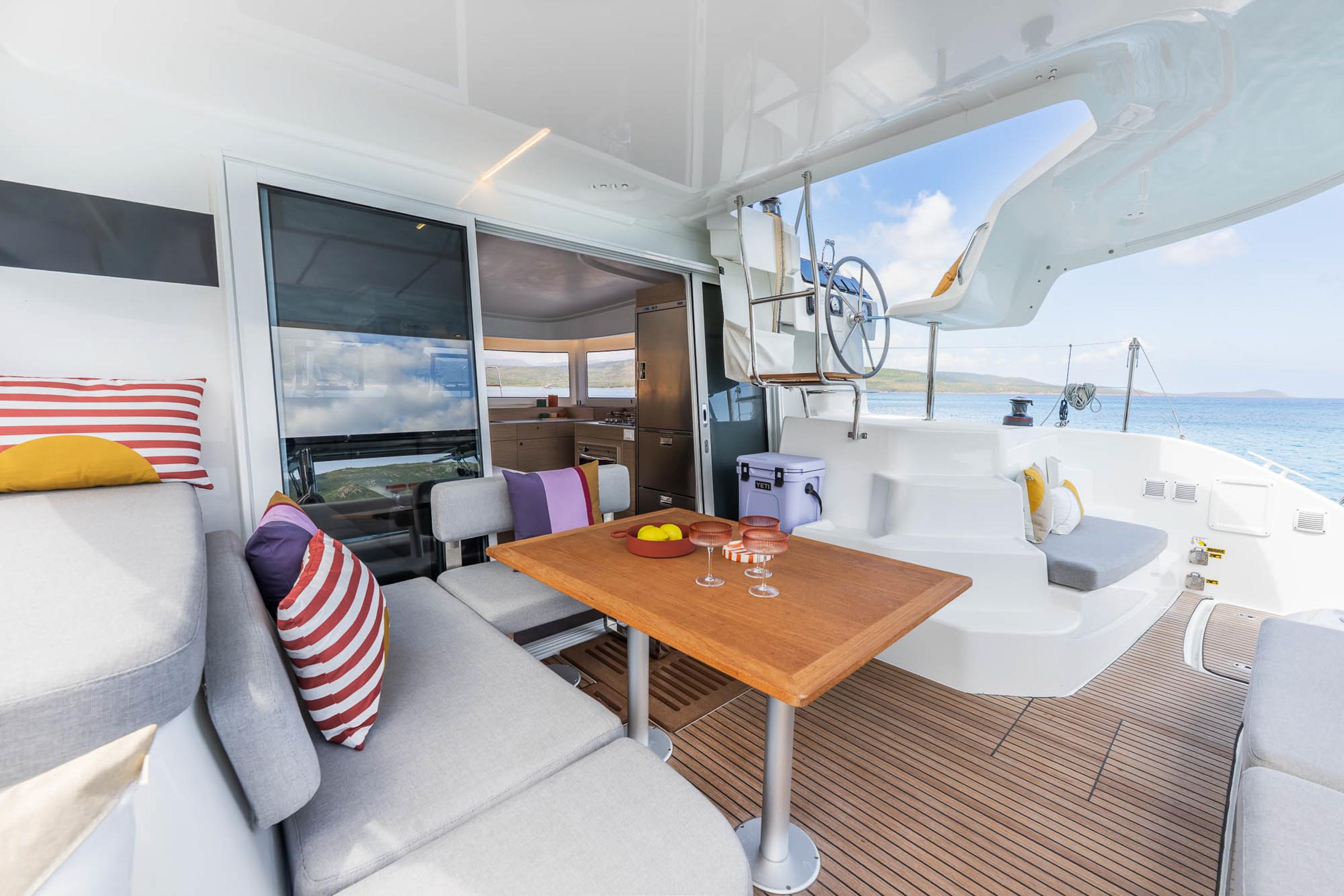 Luxurious Lagoon 38 catamaran interior, featuring modern seating, dining table, and ocean view, 2025 model.