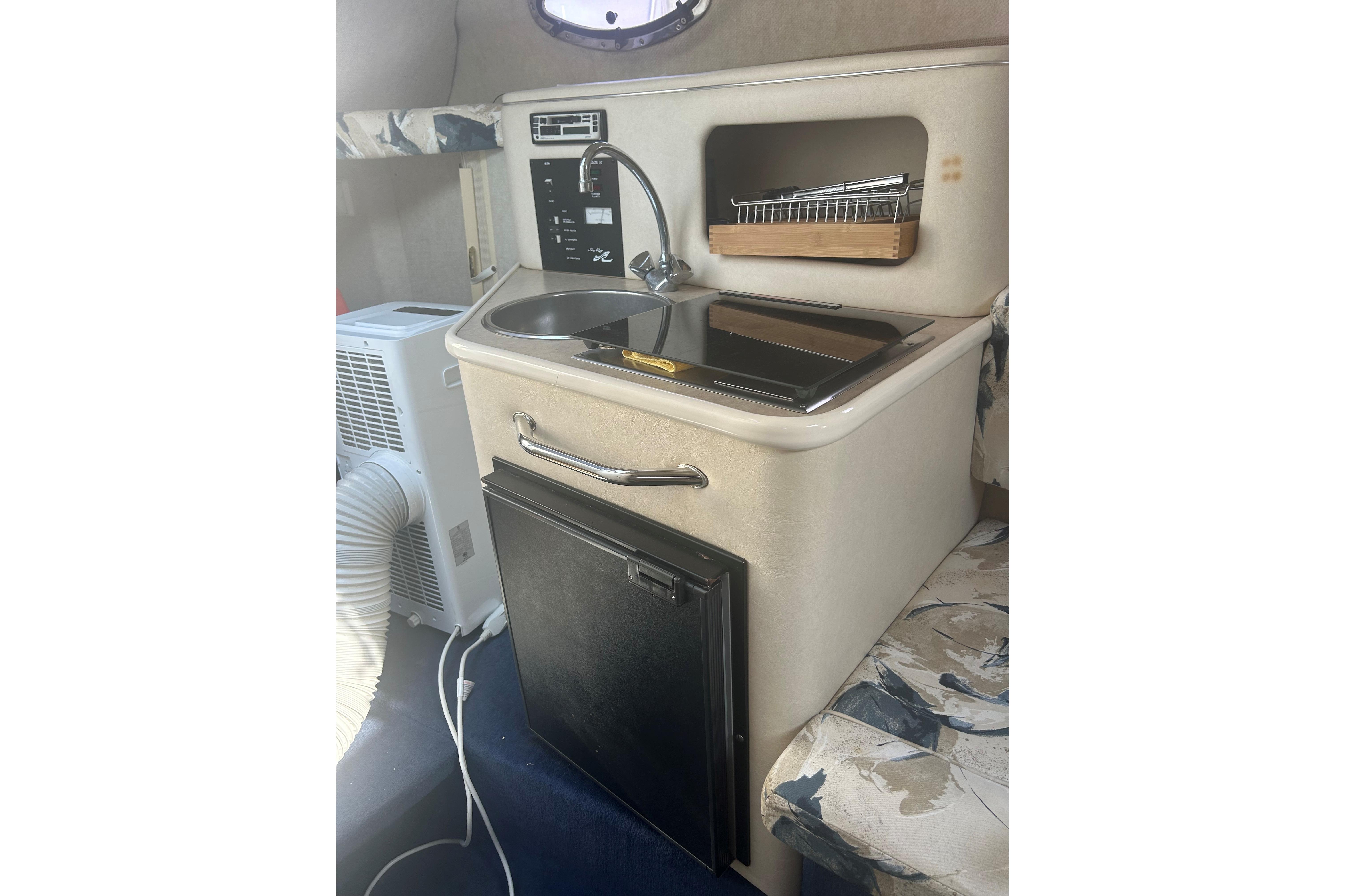 2000 Sea Ray 240 Sundancer cabin kitchenette with sink, stove, and mini-fridge.