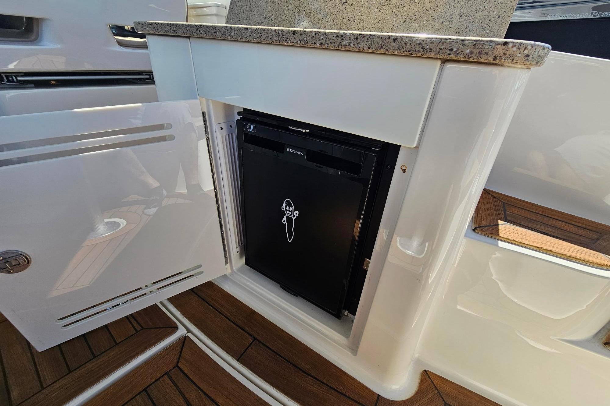 2016 Sea Ray Sundancer 350 interior with open cabinet revealing a compact refrigerator.