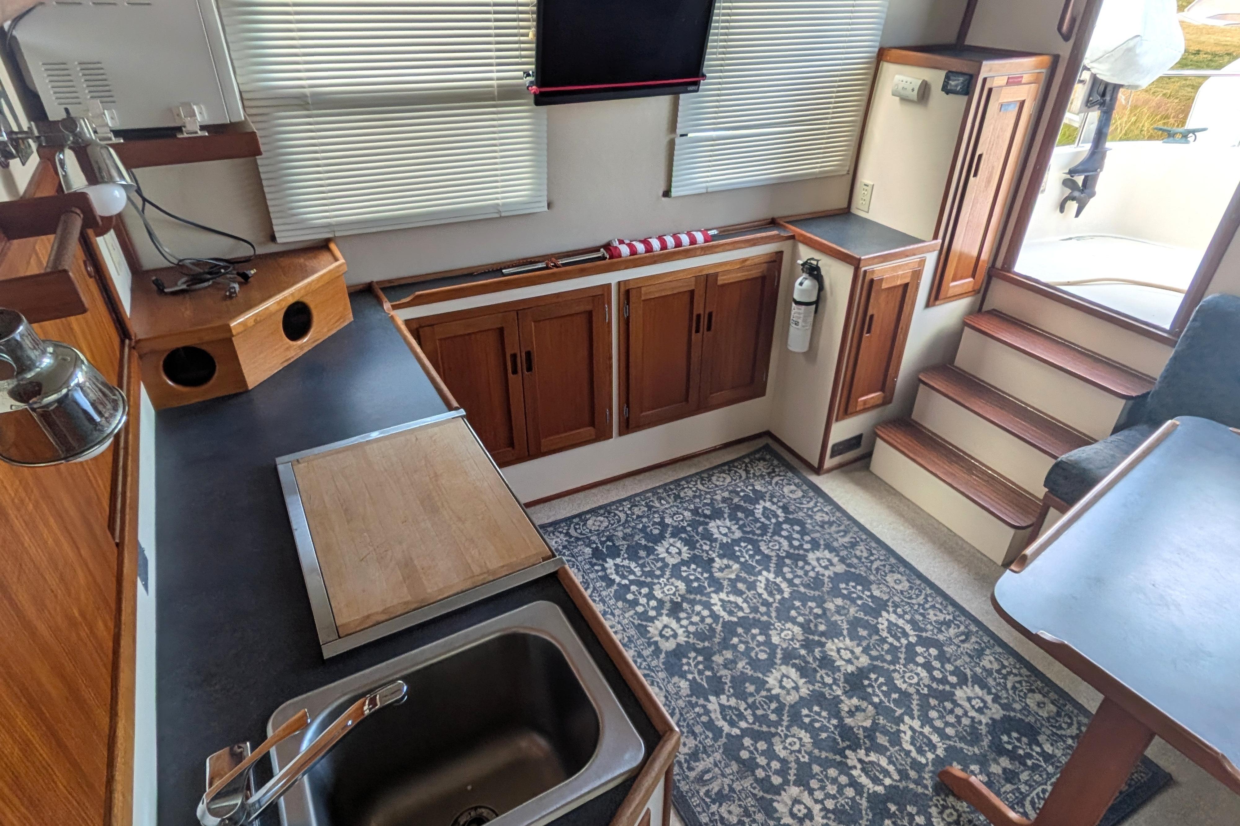Interior of a 1998 Nordic Tug 32, featuring a compact kitchen and cozy seating area.
