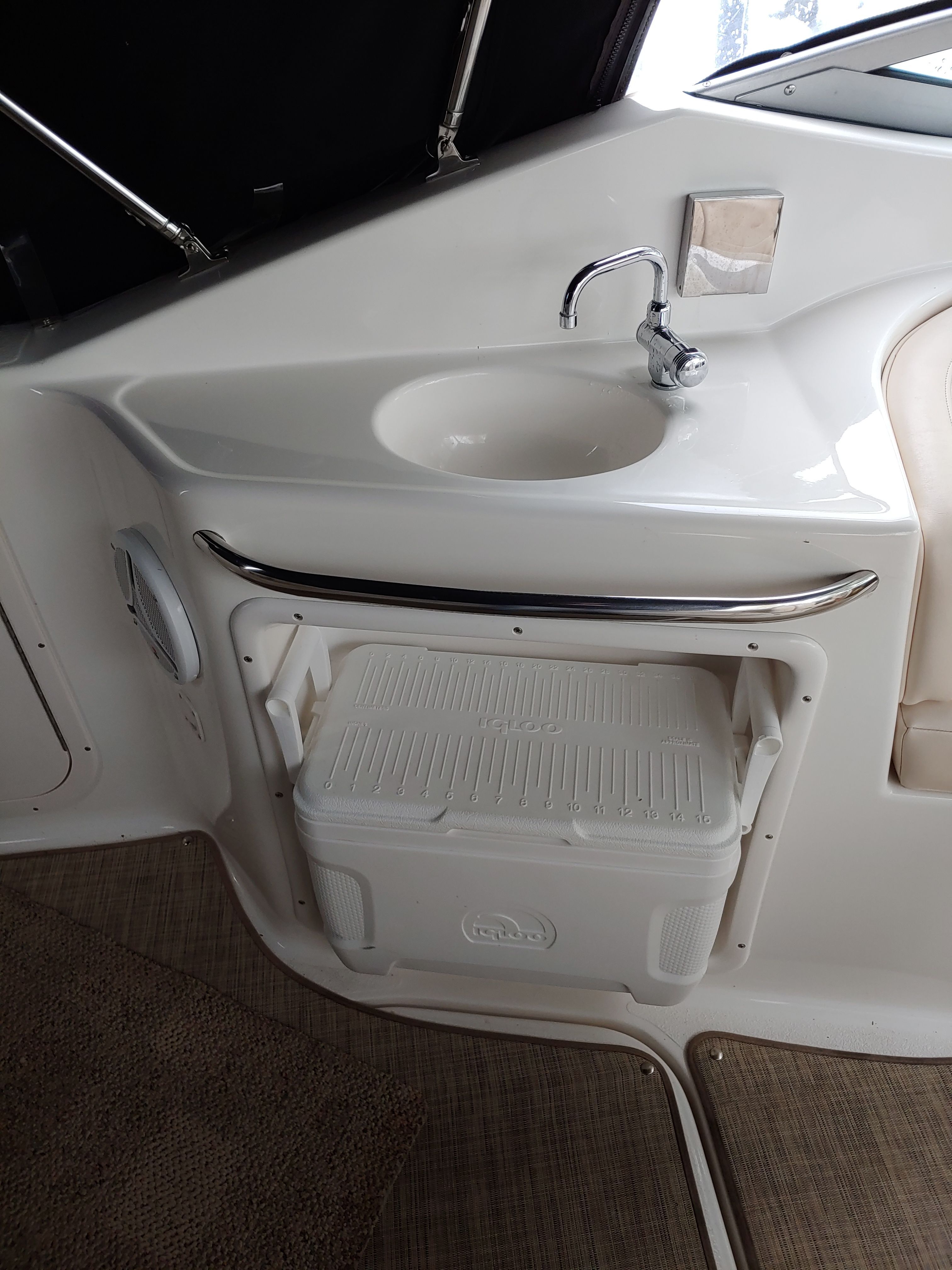 A sink with a faucet and a cooler in a boat.