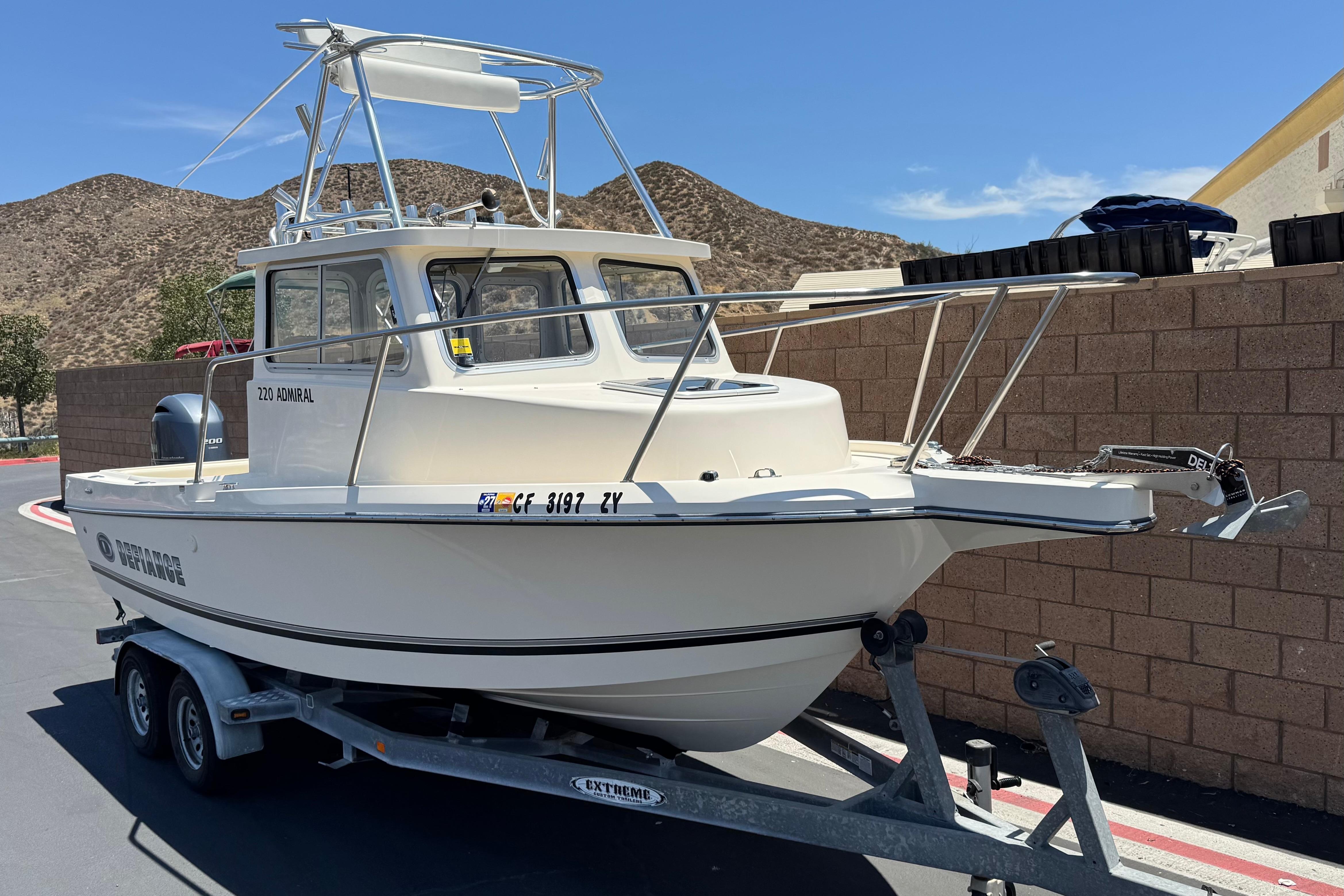 2017 Defiance Admiral 220 EX boat on trailer, parked outdoors under clear blue sky.