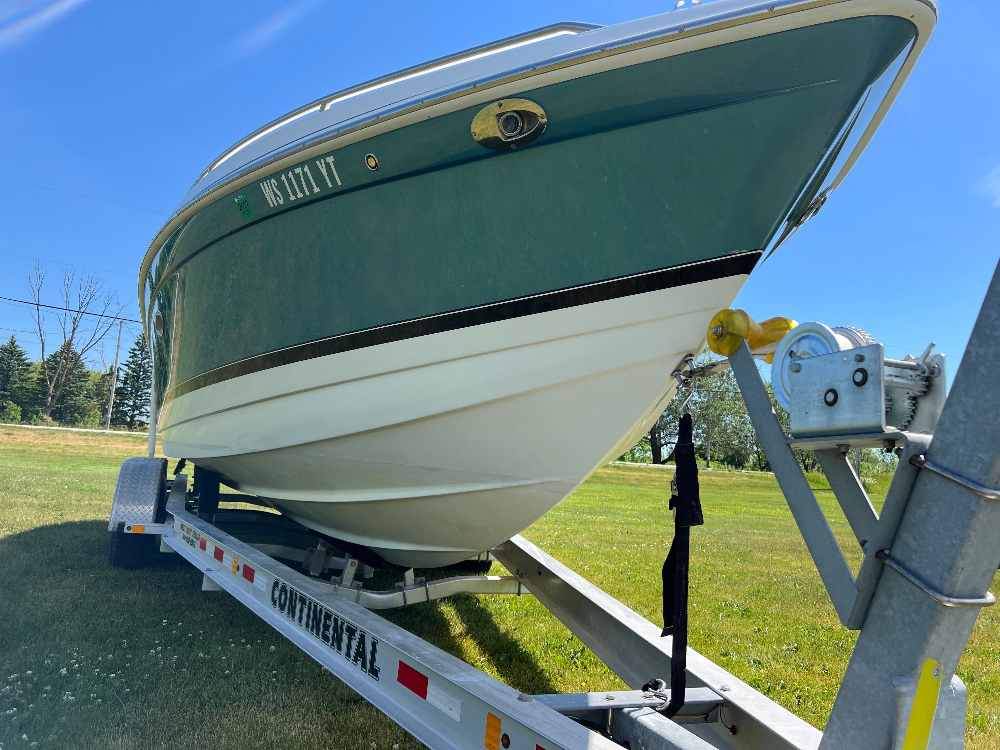 A 2005 Formula 260 Sun Sport boat on a trailer, parked on a grassy field.