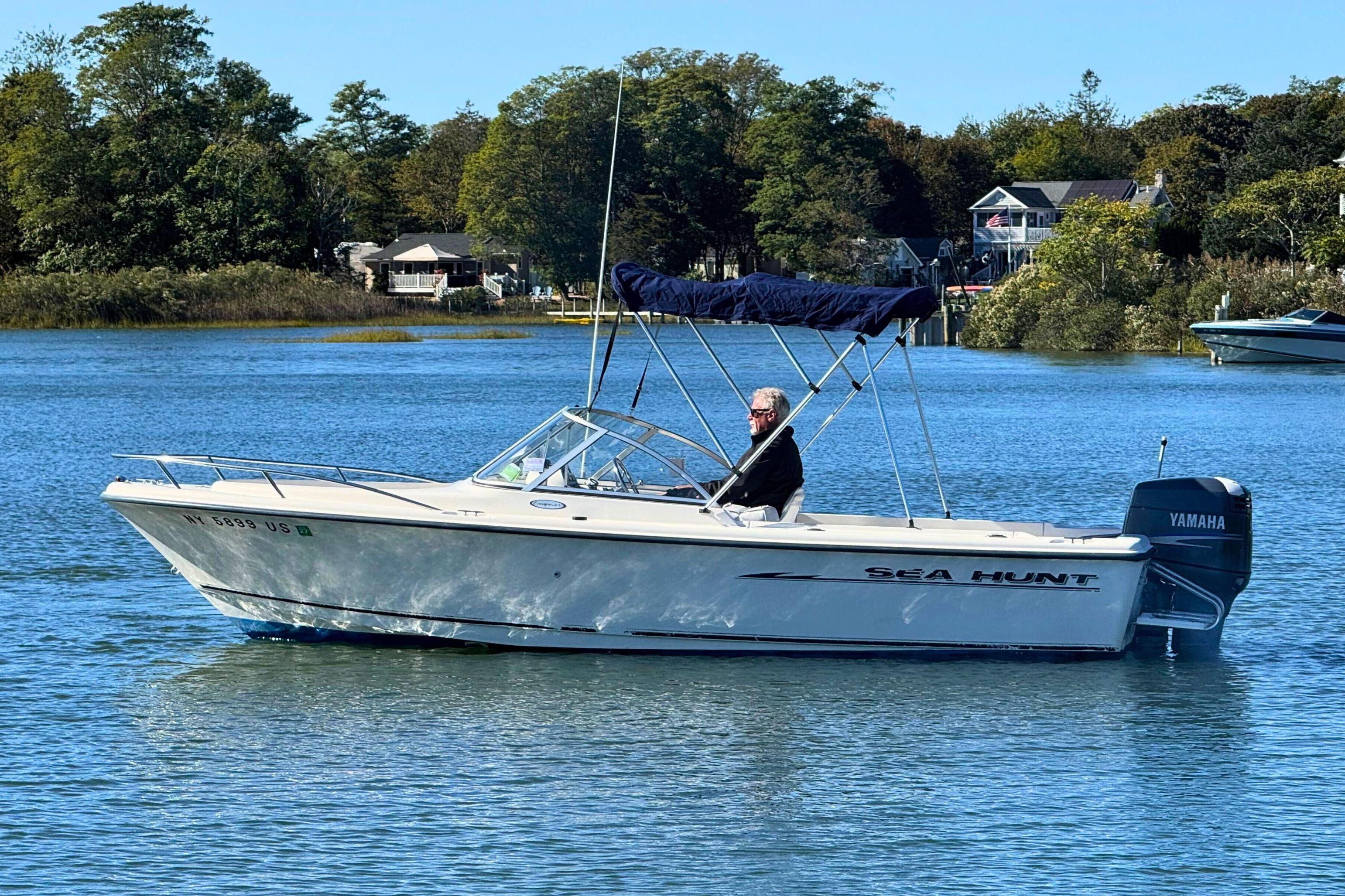 2002 Sea Hunt Escape 200 boat on calm water with trees in the background.