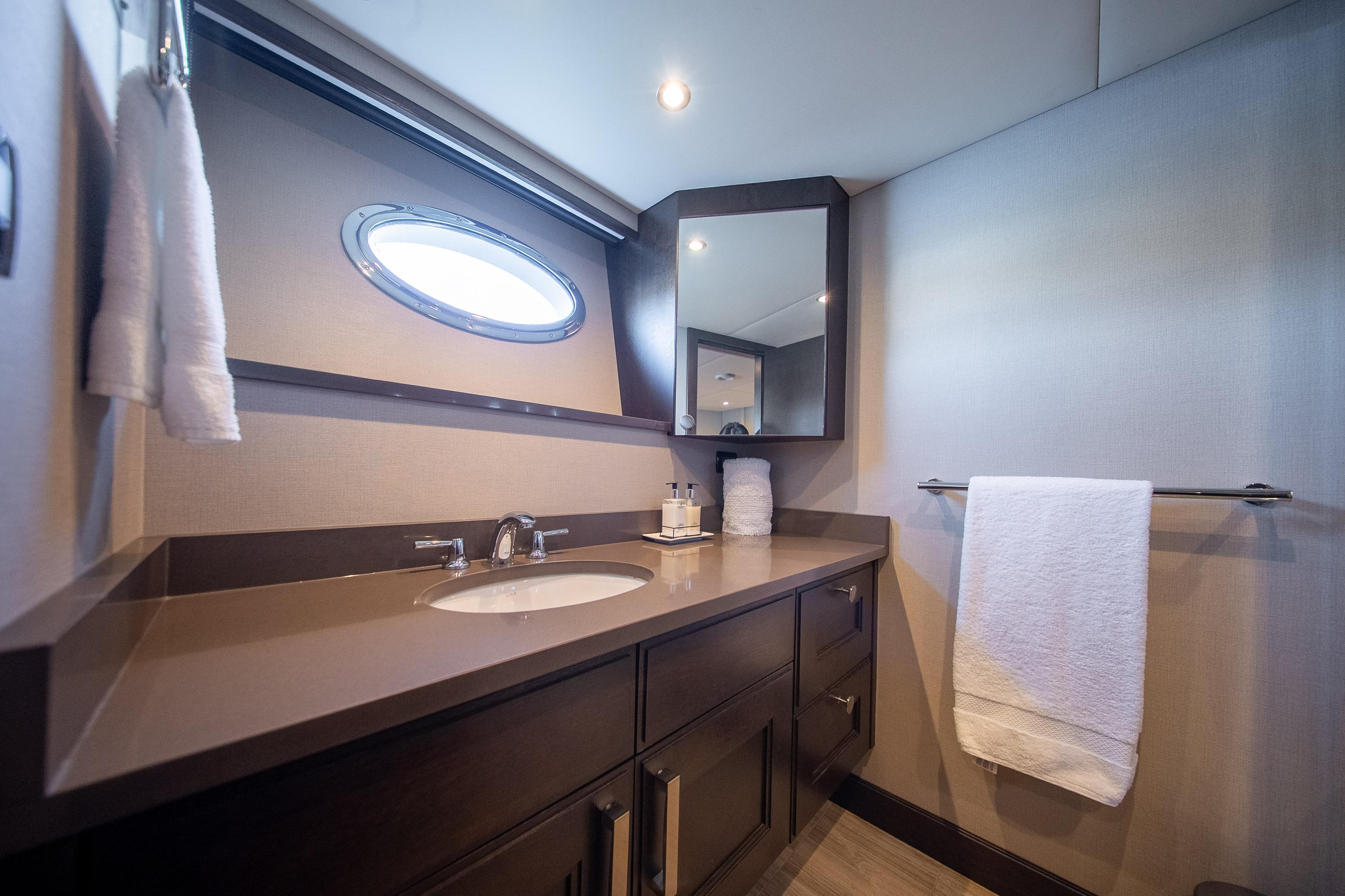 Luxurious yacht bathroom with modern fixtures, oval window, and elegant countertop, Crescent Custom 1992.