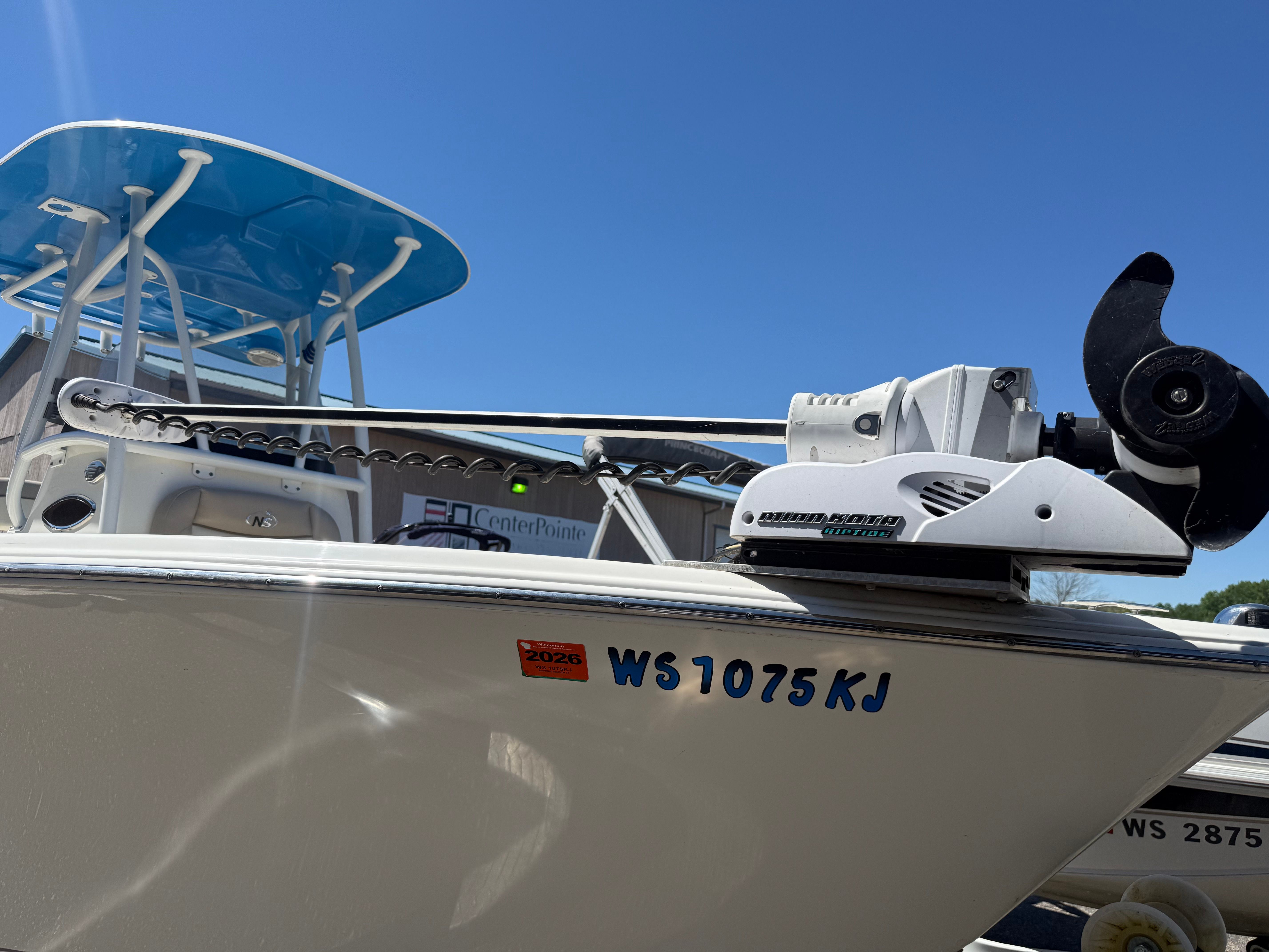 A NauticStar 22 XS boat with a blue canopy and motor, on a trailer.