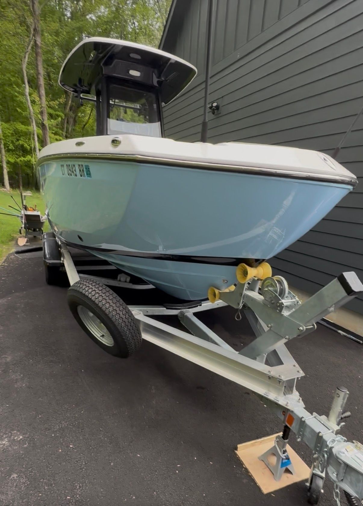 A 2024 Yamaha 255 FSH Sport H boat on a trailer beside a building.