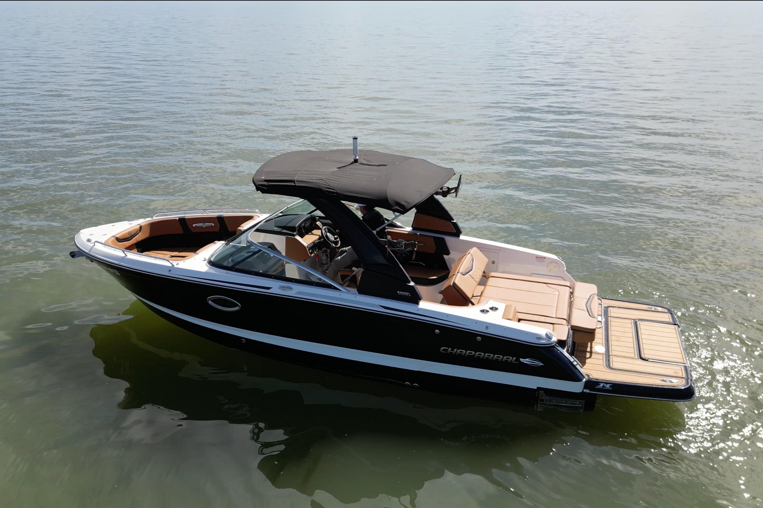 2023 Chaparral 26 Surf boat on calm water, featuring sleek design and spacious seating.