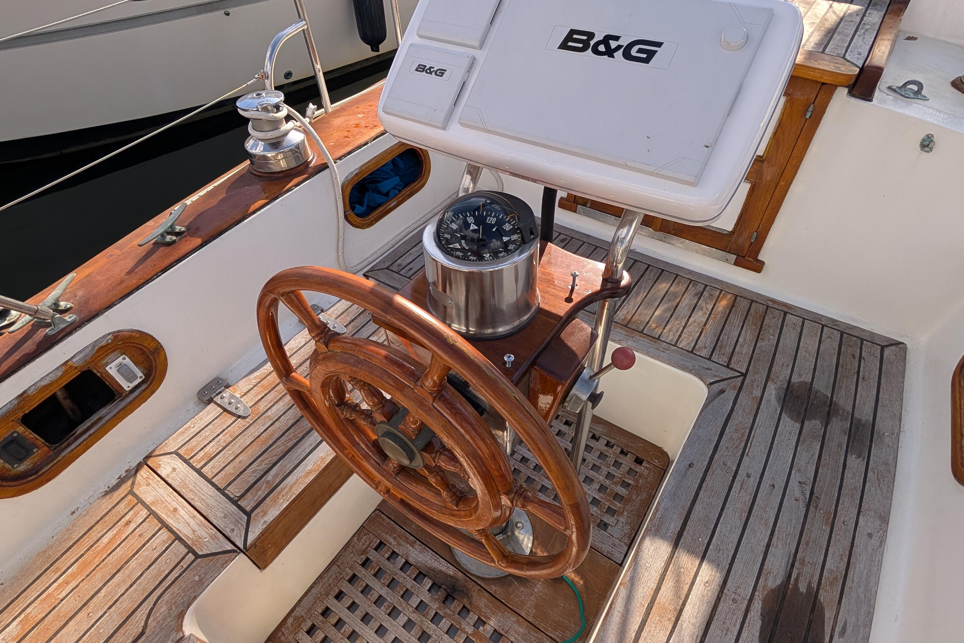 Wooden steering wheel and compass on a 1983 Robert Perry 41 sailboat deck.