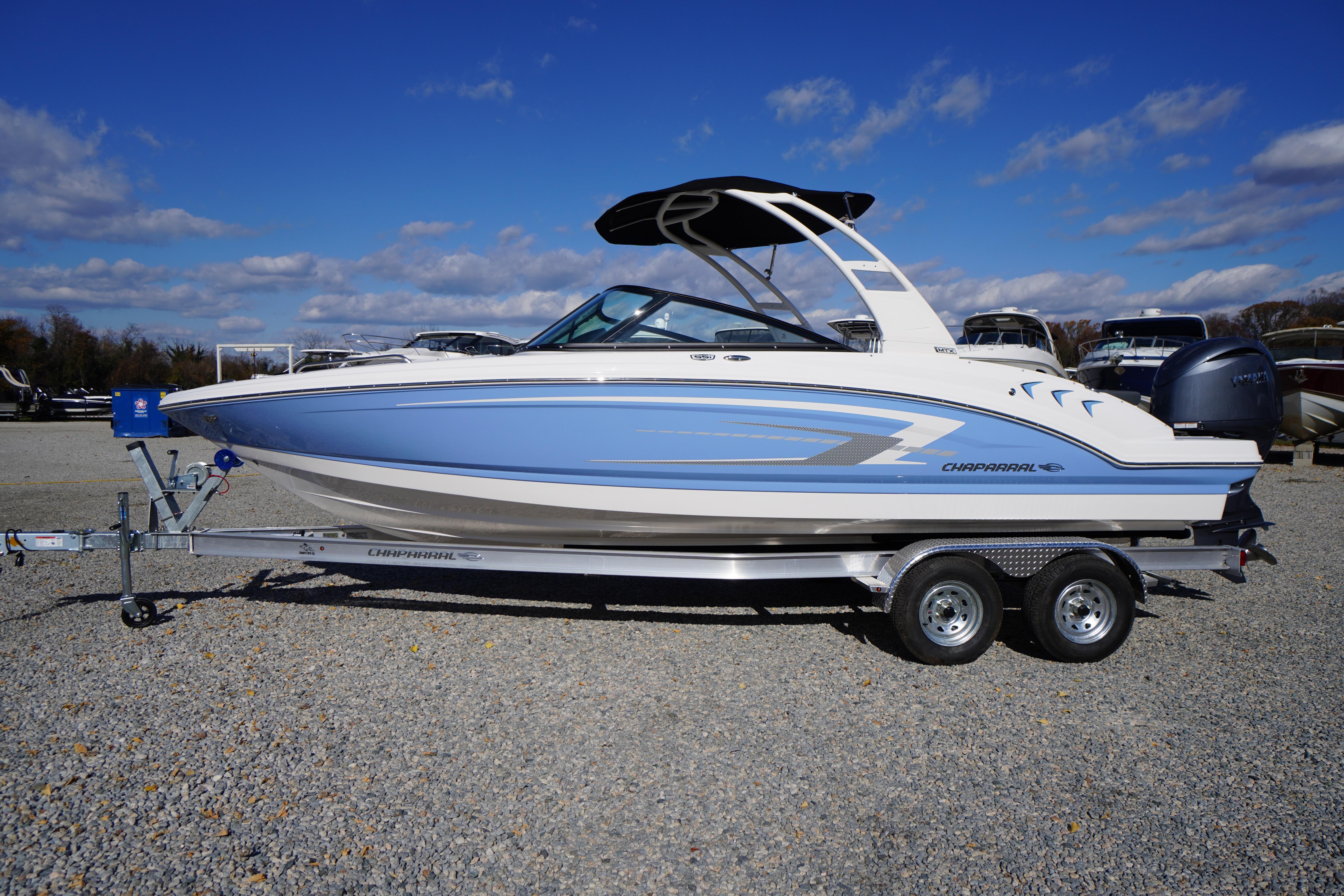 2026 Chaparral 23 SSi OB boat on trailer, blue and white design, parked outdoors.