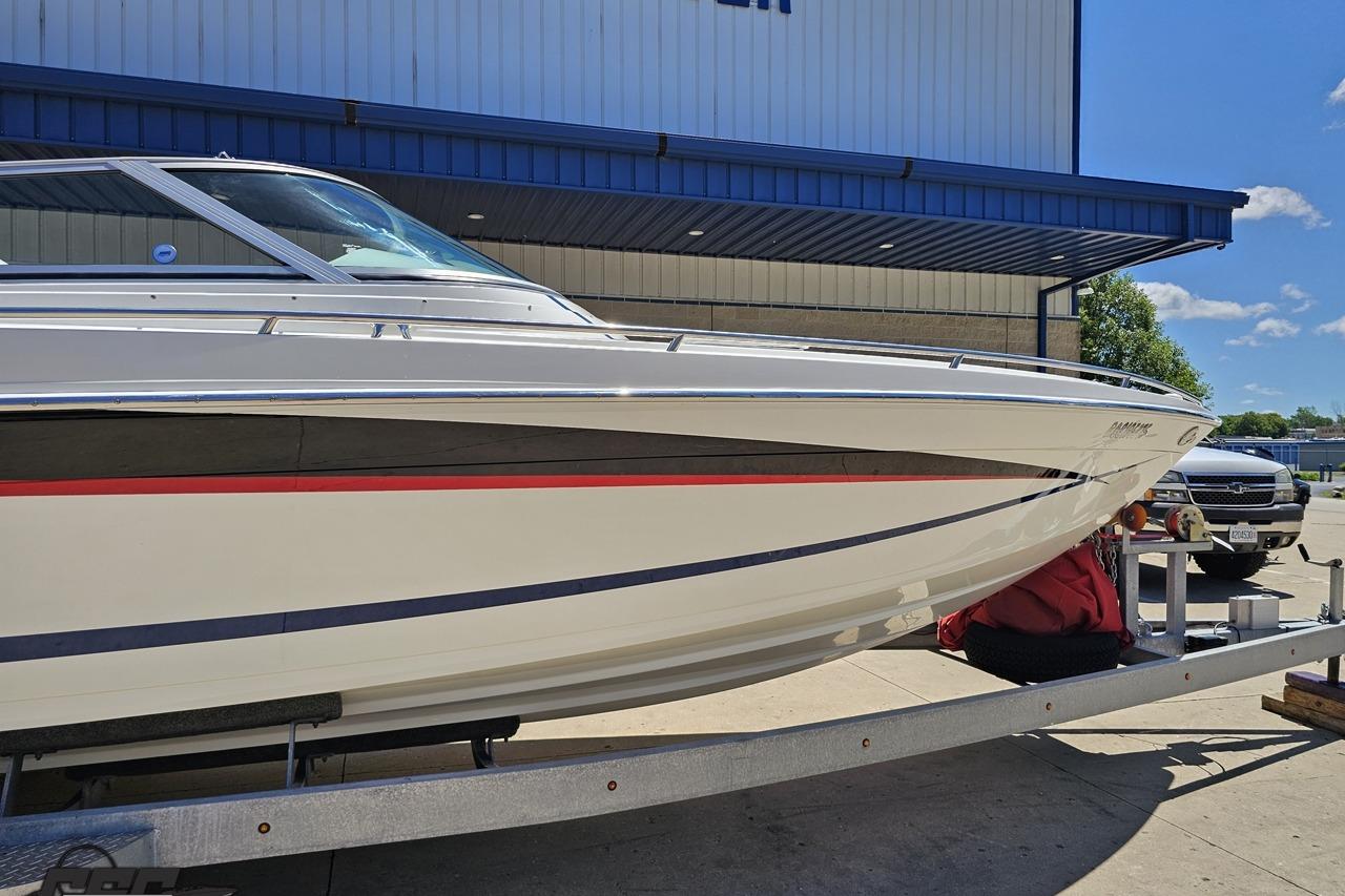 2005 Formula 271 FASTech boat on trailer outside a building under blue sky.