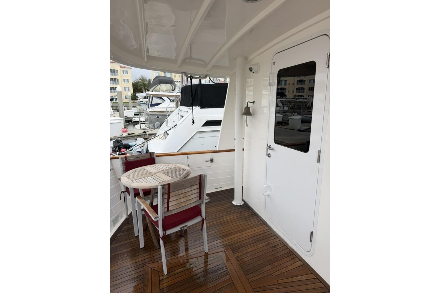 2005 Kadey-Krogen 44 yacht deck with table and chairs, featuring wooden flooring.