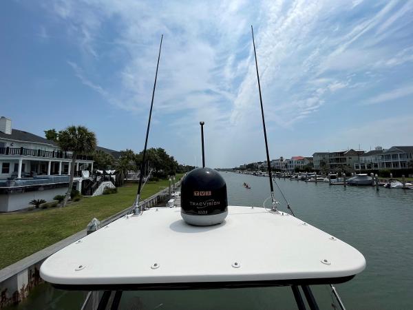 2020 Scout 420 LXF boat on a canal, surrounded by waterfront homes under a partly cloudy sky.