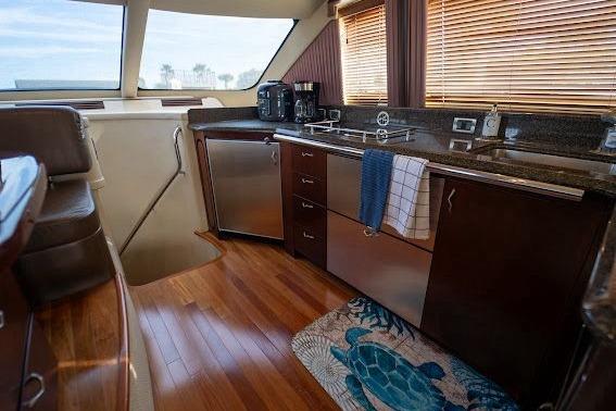 Luxurious 2006 Sea Ray 580 Sedan Bridge yacht kitchen with modern appliances and wooden flooring.