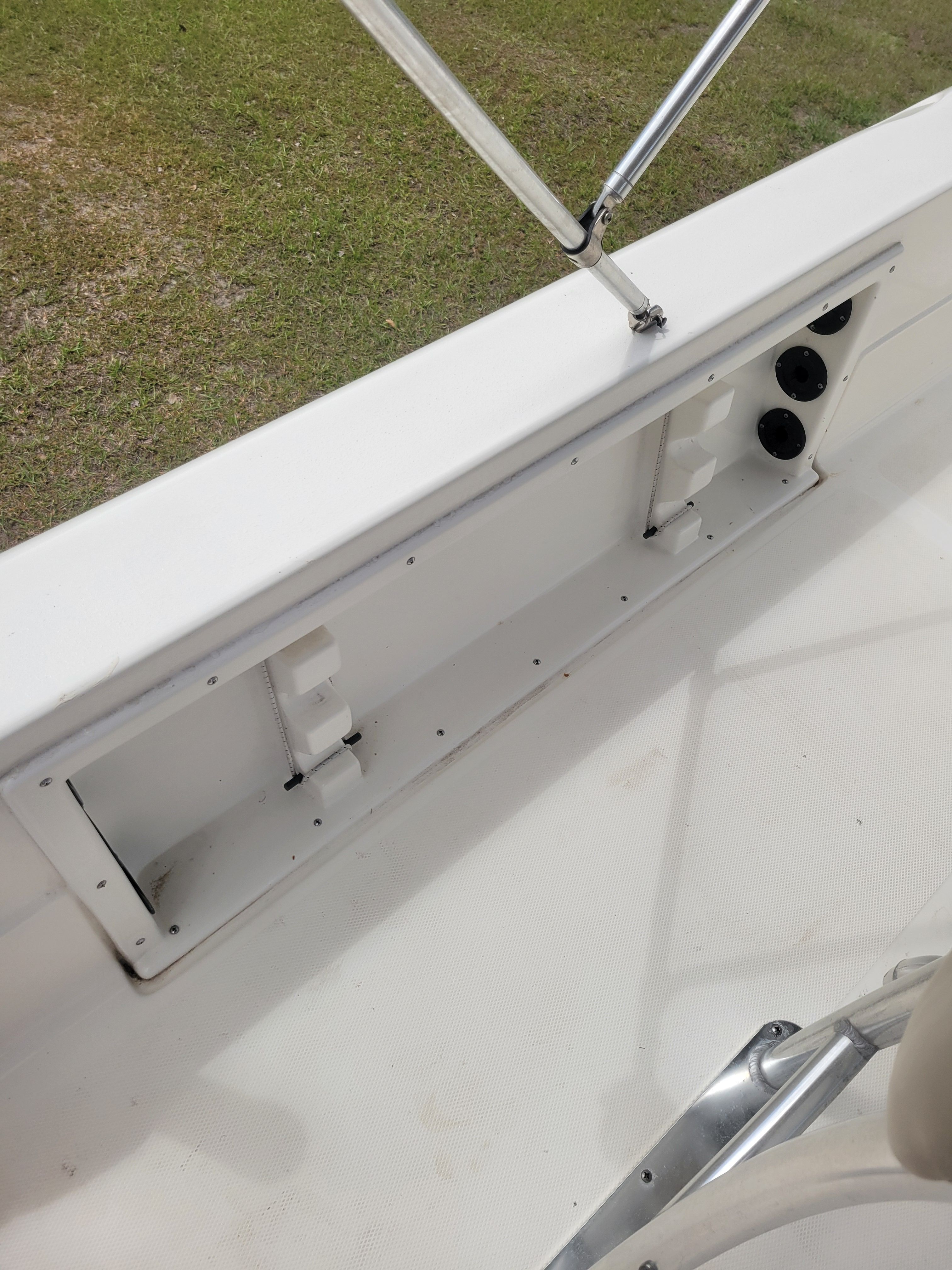A white boat with an open storage compartment and a railing.