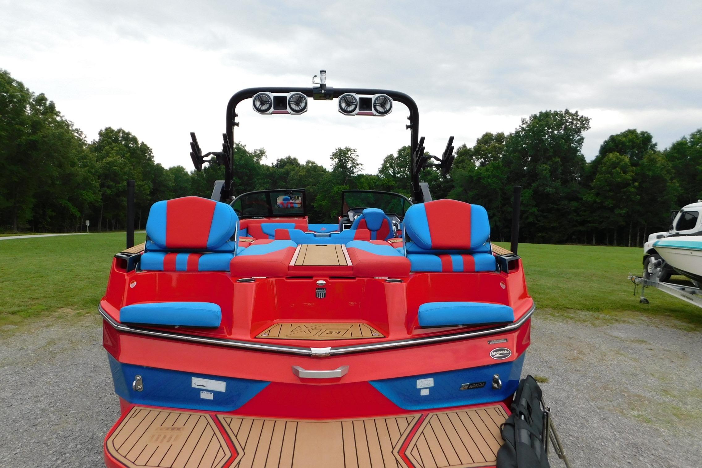2022 MasterCraft NXT24 boat with vibrant red and blue seating, parked outdoors.