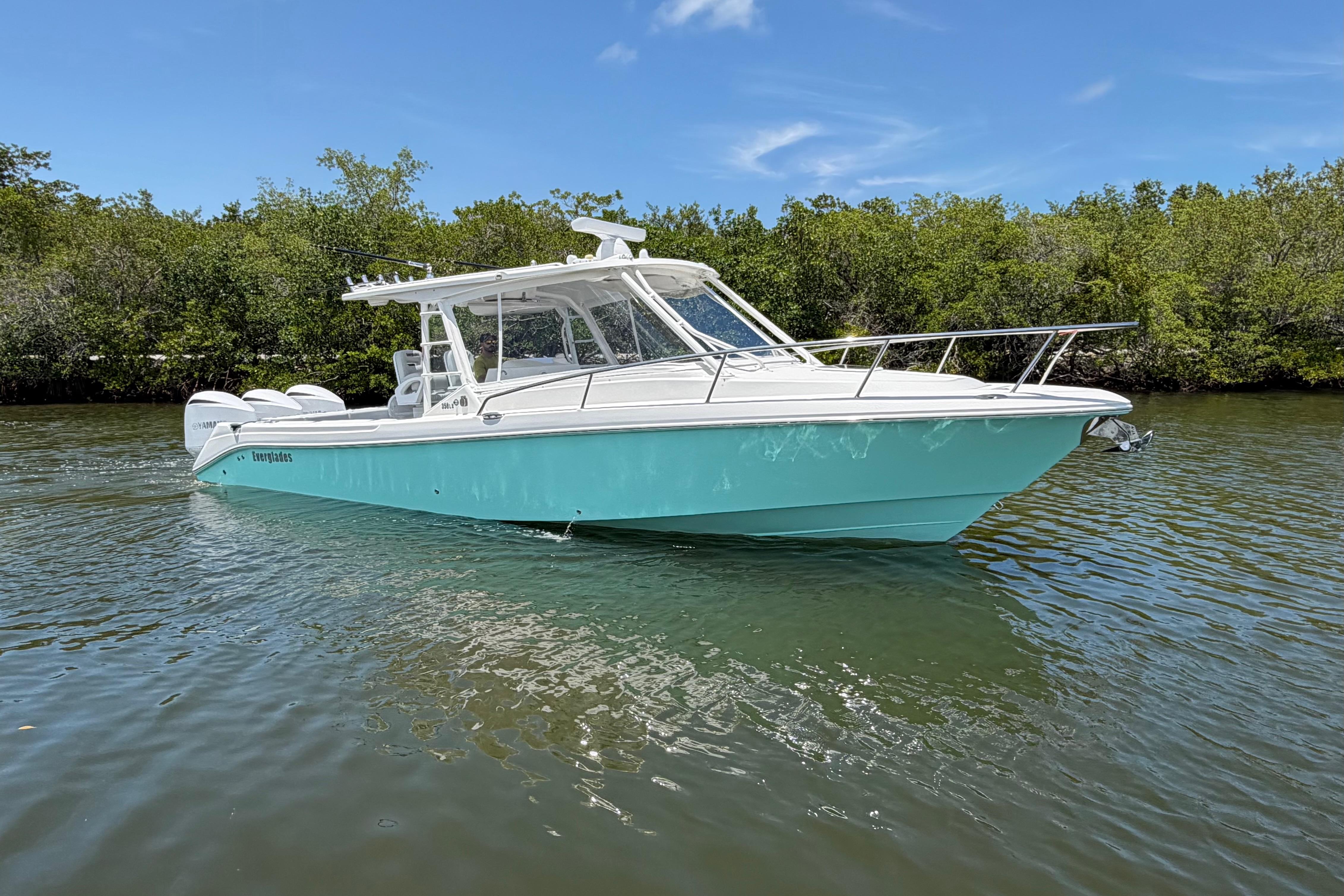 2009 Everglades 350LX boat on calm water, surrounded by lush greenery under a clear blue sky.