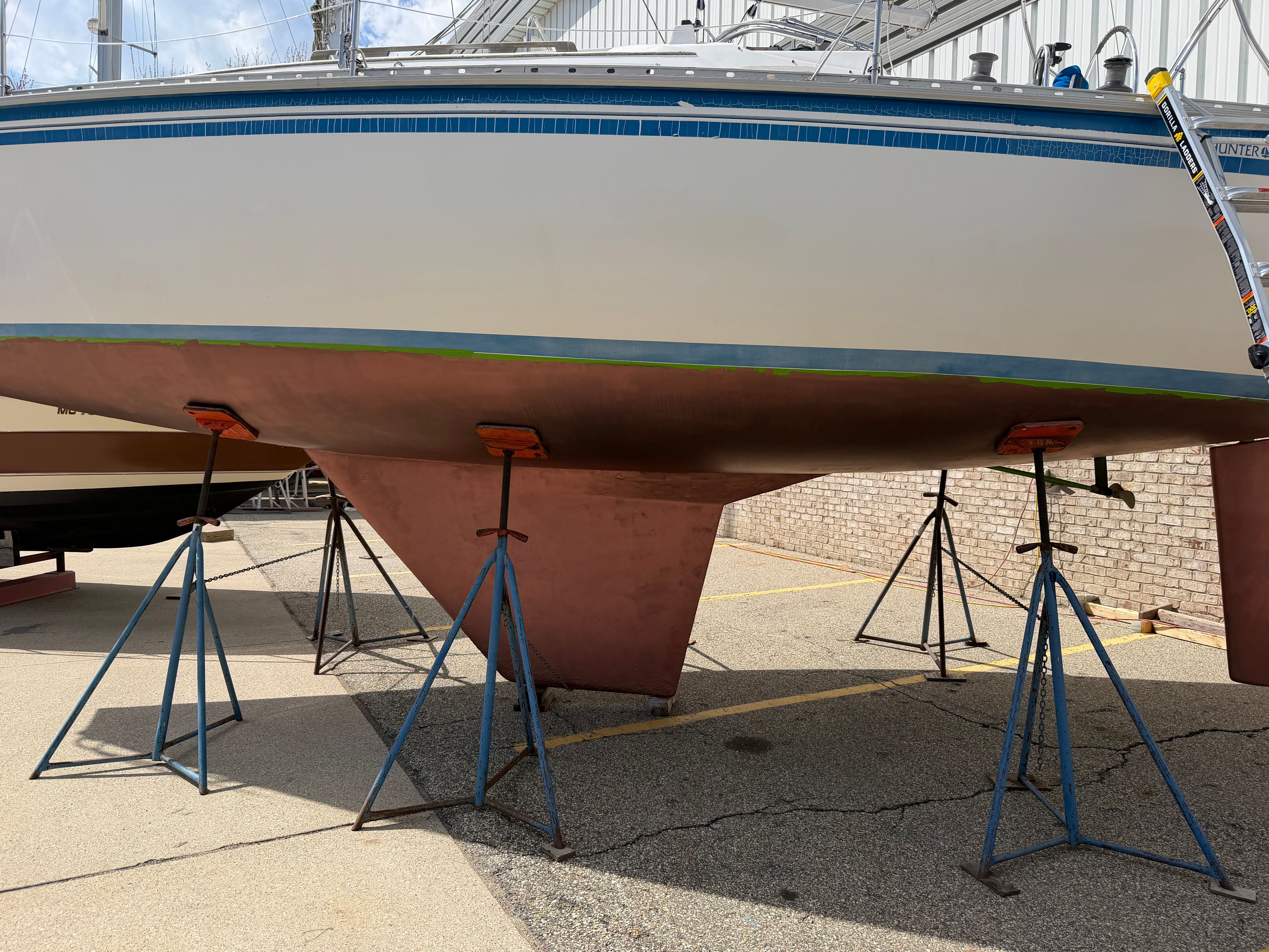 A 1986 Hunter 31 boat is on stands on land.