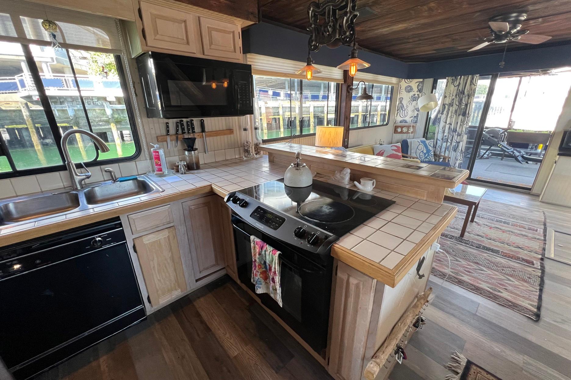 Cozy 1993 Sumerset houseboat kitchen with wooden cabinets, stove, and waterfront view.