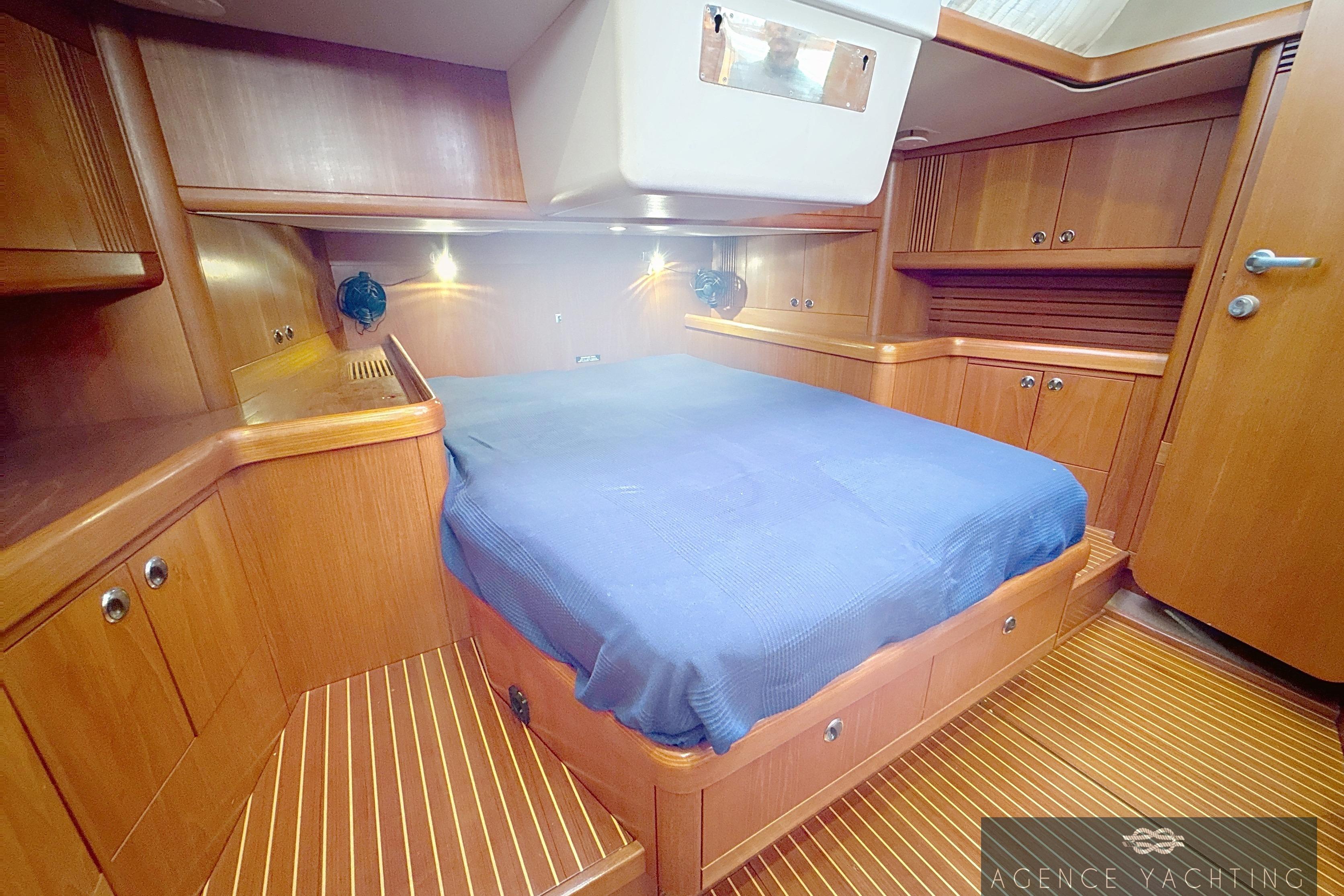 Luxurious 2003 Nautor Swan 48 yacht cabin with wooden interior and cozy bed.