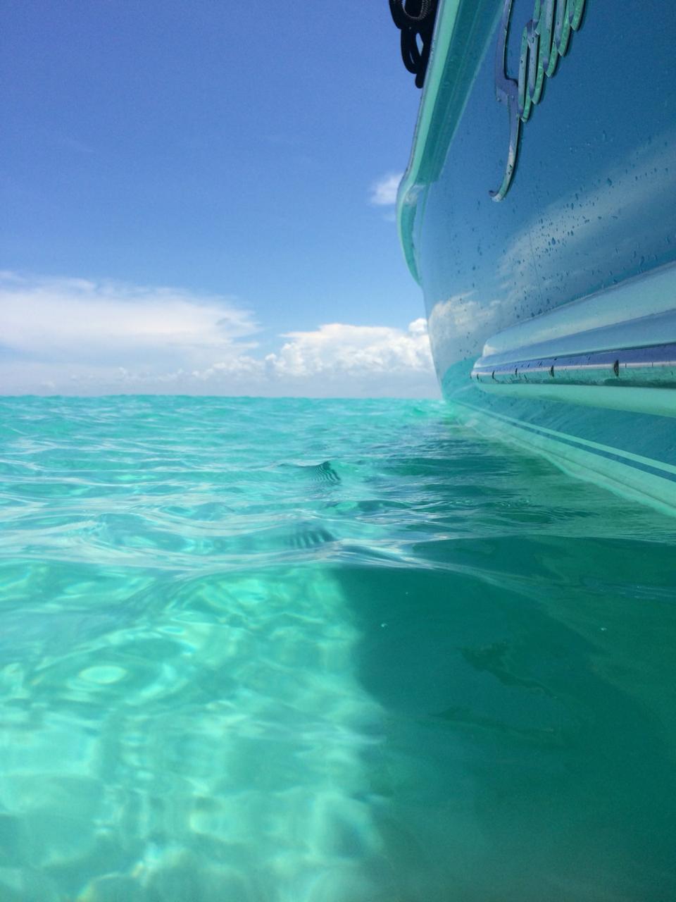 2013 Scout 245 Dorado boat on clear turquoise water under blue sky.
